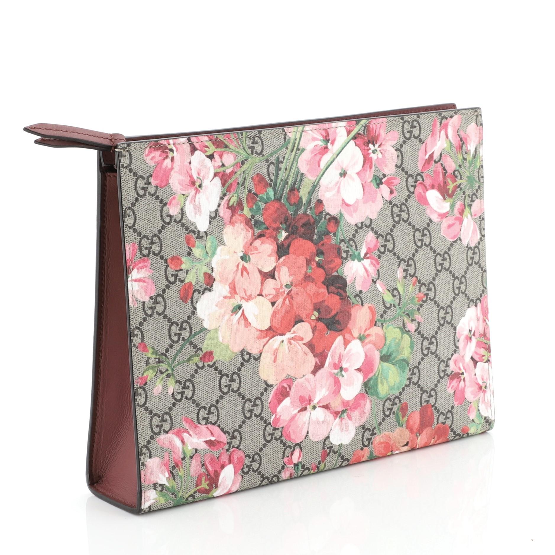 This Gucci Toiletry Pouch Blooms Print GG Coated Canvas Large, crafted from brown GG coated canvas with pink blooms print overlay, features leather sides and silver-tone hardware. Its zip closure opens to a brown satin interior with slip