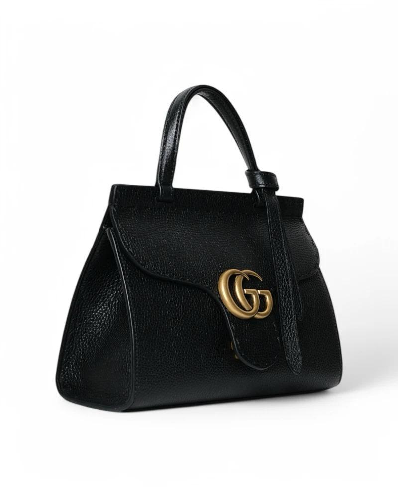 Gucci signature bag, Marmont line, Top Handle model in medium size, made of black grained leather with gold hardware. Features a flap with classic gold metal 