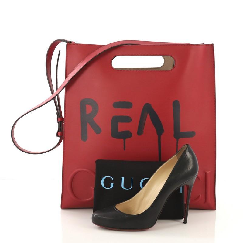 This Gucci Tote GucciGhost Leather Medium, crafted from red leather, features cutout top handles, black GucciGhost print, debossed logo across baseline and gold-tone hardware. Its wide open top showcases a beige microfiber interior. **Note: Shoe