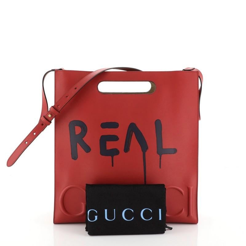 This Gucci Tote GucciGhost Leather Medium, crafted from red leather, features cutout top handles, GucciGhost print, debossed logo across baseline, and aged gold-tone hardware. Its wide open top showcases a neutral microfiber interior. 

Estimated