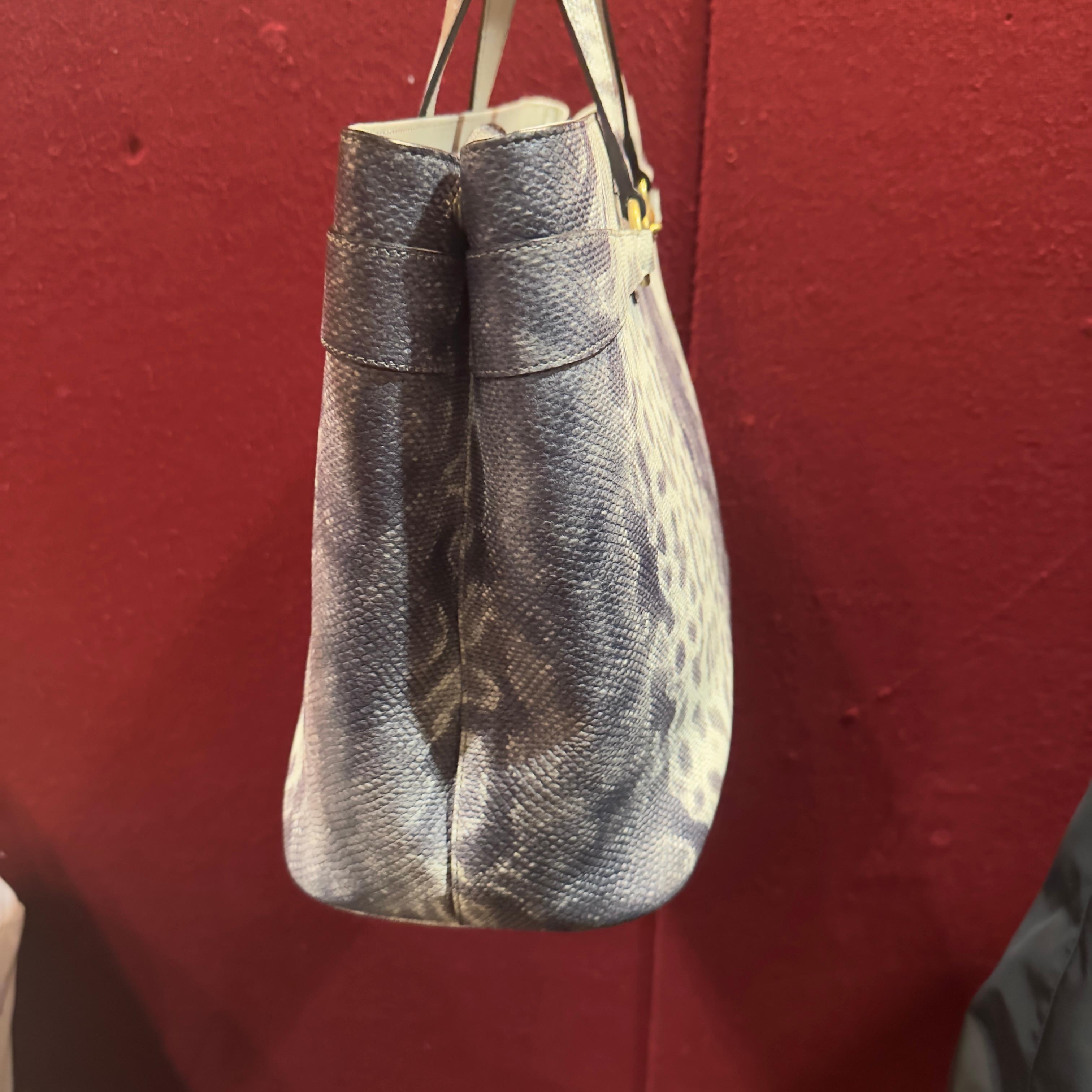 Questa tote Gucci è una proposta rara e ricercata, caratterizzata da una particolare stampa effetto anaconda nei toni del grigio, con una texture ricca e tridimensionale che richiama le lavorazioni esotiche della Maison. Un modello capiente,