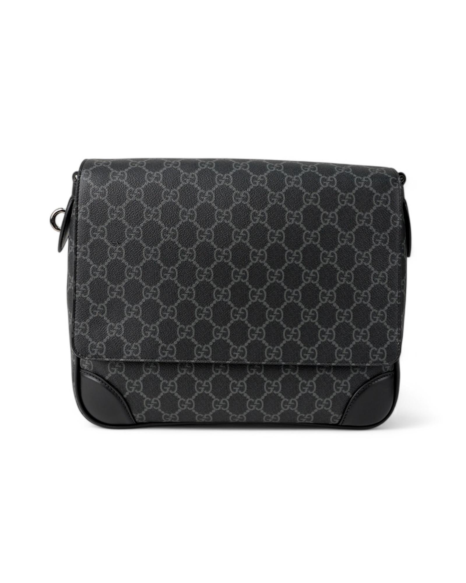 Borsa firmata Gucci, modello Emblem nella misura medium, realizzata in tela nera con la fantasia GG Supreme, inserti in pelle e dettagli in hardware argentato. Dotata di una patta frontale con chiusura magnetica, l’interno è rivestito in tela beige