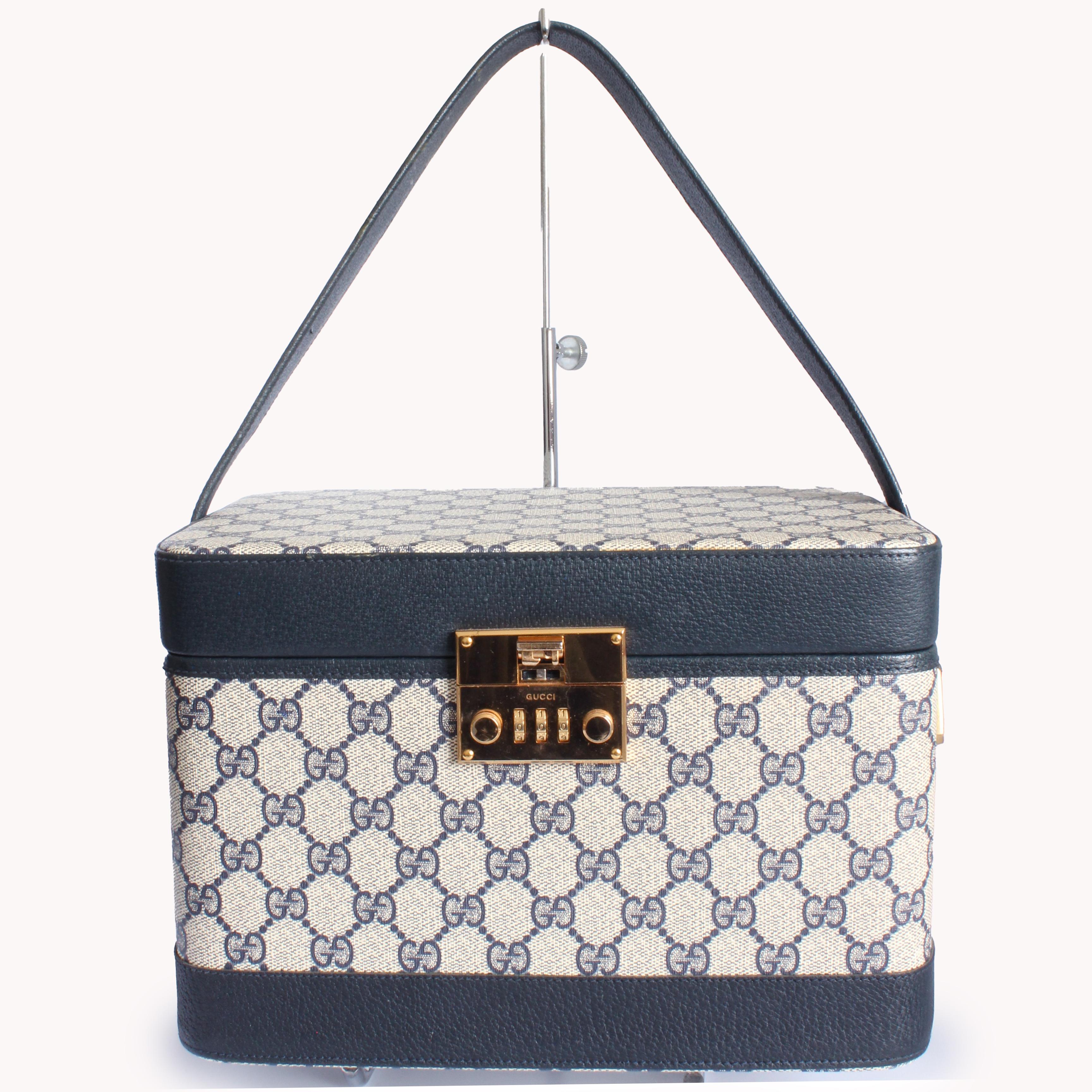 Viaja con estilo con este increíble maletín de tren vintage fabricado por GUCCI, probablemente en la década de 1980.  Está confeccionada con su emblemática lona con el logotipo GG, ribeteada en piel azul marino y con herrajes dorados.  El interior