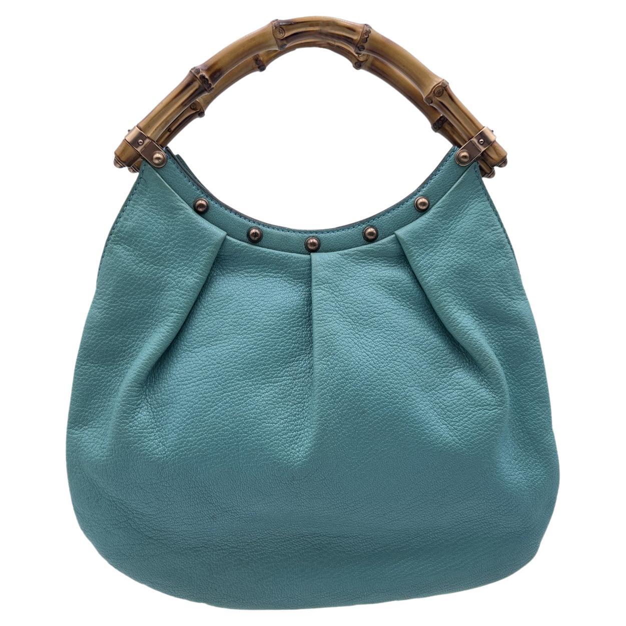 Beautiful small tote handbag by Gucci, crafted in turquoise leather with bamboo handles. It features rose gold tone hardware, studs detailing on top, an open top, turquoise canvas lining and 1 side open pocket inside. 'GUCCI - Made in Italy' tag