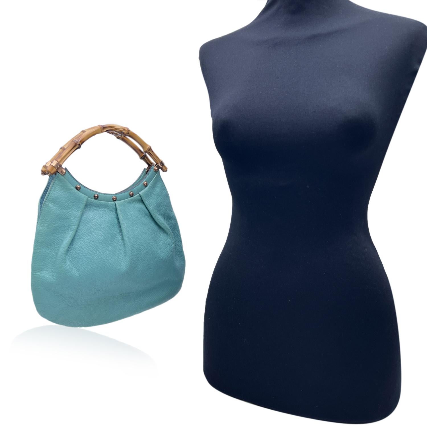 Beautiful small tote handbag by Gucci, crafted in turquoise leather with bamboo handles. It features rose gold tone hardware, studs detailing on top, an open top, turquoise canvas lining and 1 side open pocket inside. 'GUCCI - Made in Italy' tag
