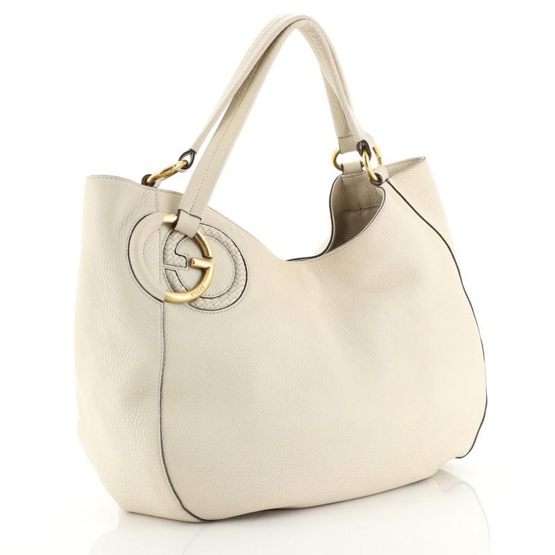 This Gucci Twill Shoulder Bag Leather, crafted in neutral leather, features dual shoulder straps, interlocking G with engraved logo, and gold-tone hardware. Its hook-clasp closure opens to a neutral fabric interior with zip and slip pockets.