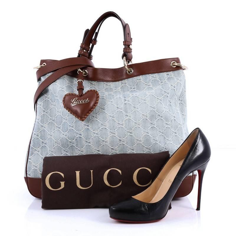 This authentic Gucci Valentine Convertible Tote GG Denim Large is a stylish and gorgeous accessory. Crafted in light blue GG monogram denim with brown leather trims, this tote features dual leather handles, padded leather heart charm, protective