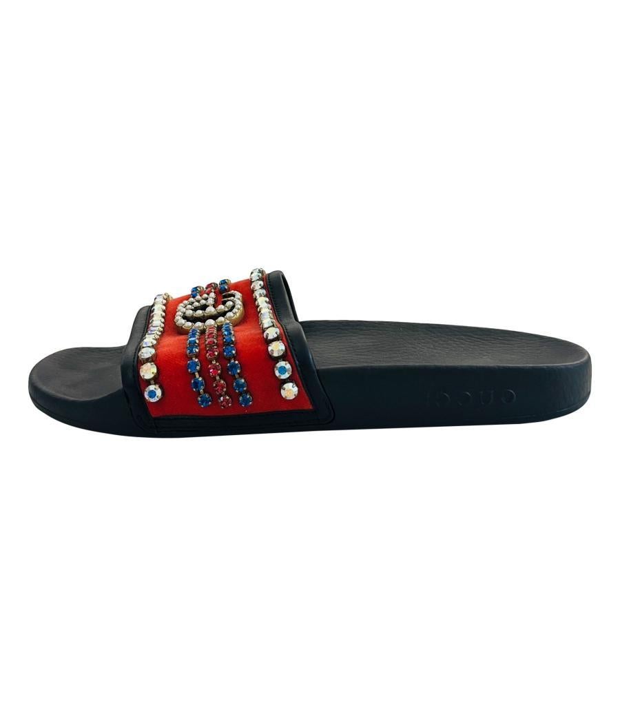 Gucci Velvet 'GG' Crystal Embellished Slide Sandals
Black rubber slides designed with red velvet stripe detailed with pearl lined double 'G' to the centre and trimmed with white crystals.
Featuring blue and red crystal embellishment inspired by the