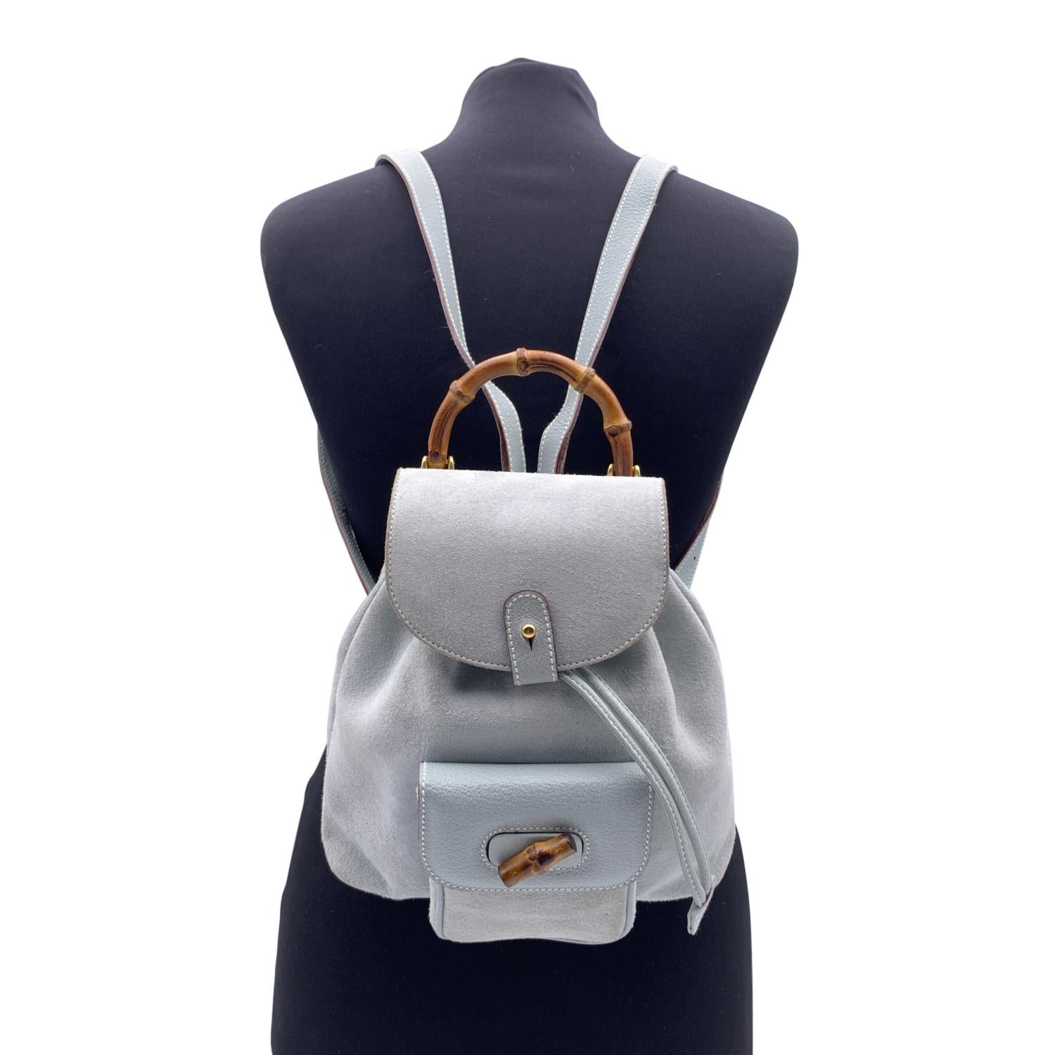 Vintage small backpack by Gucci, crafted in baby blue suede. It features Bamboo handle and and knob. 1 front pocket with twist lock closure. Flap closure and drawstring top opening. Gold metal hardware. Internal diamond lining. 1 side zip pocket