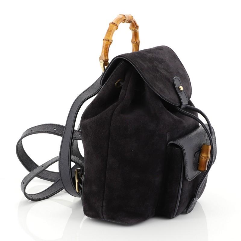 This Gucci Vintage Bamboo Backpack Suede Mini, crafted from blue suede, features a bamboo top handle, adjustable backpack straps, leather trim, exterior front pocket with bamboo twist-lock closure, and aged gold-tone hardware. Its drawstring top