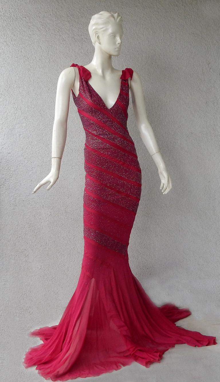 Fabelhaftes Gucci Vintage-Kleid mit rotem Schrägschnitt, verziert mit spiralförmigen Paneelen, die mit handgefertigten Perlen besetzt sind.   Mit tiefem Ausschnitt und zarter Schnürung an der Schulter. Pfützen mit langem Rock mit voller Schleppe.