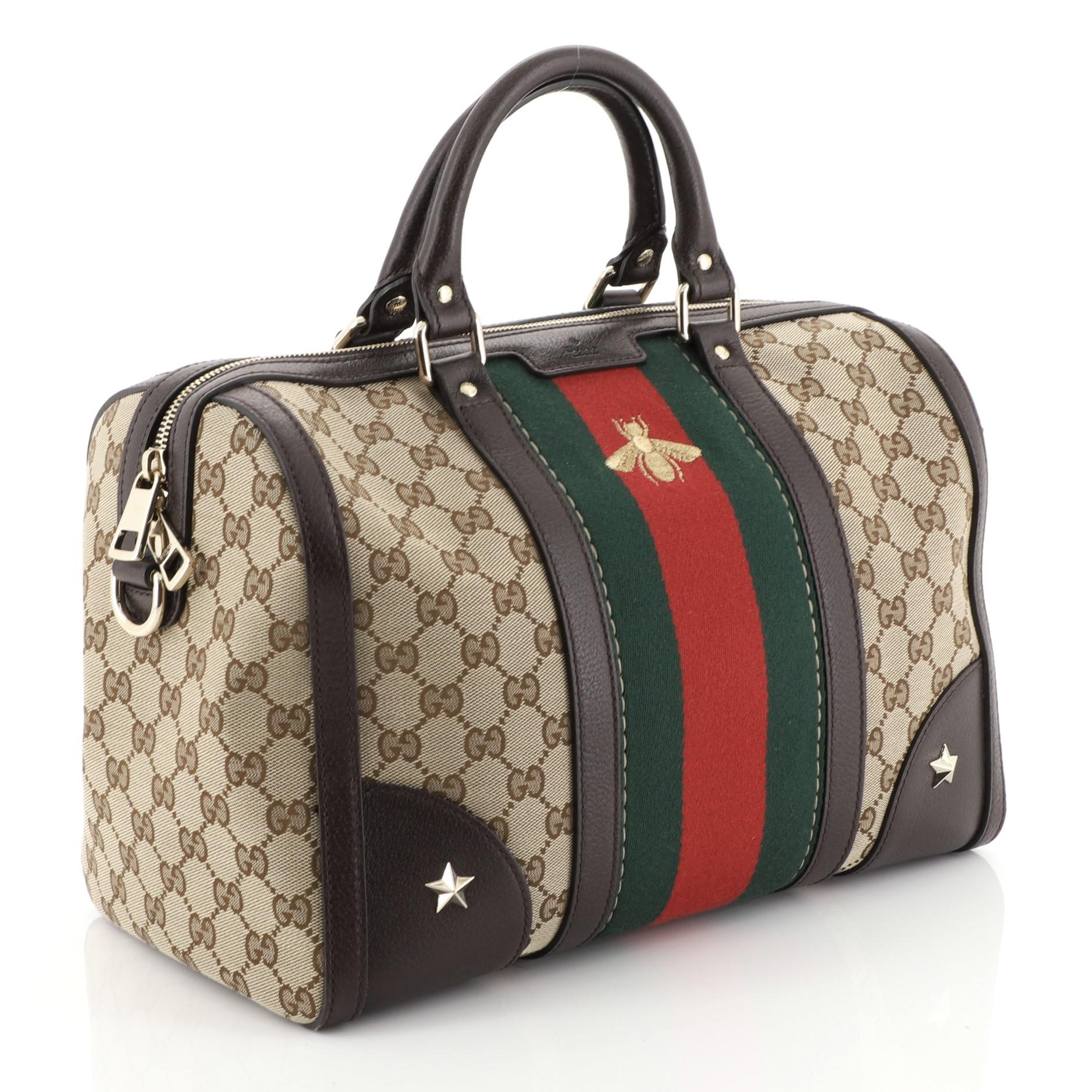 This Gucci Vintage Bee Web Boston Bag GG Canvas Medium, crafted with brown GG canvas with brown leather trims, features signature iconic Gucci green and red web stripe with a golden embroidered bee at the front, dual-rolled handles, protective base