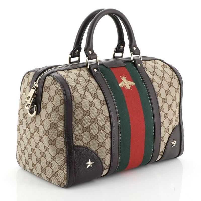 This Gucci Vintage Bee Web Boston Bag GG Canvas Medium, crafted with brown GG canvas with brown leather trims, features signature iconic Gucci green and red web stripe with a golden embroidered bee at the front, dual-rolled handles, protective base