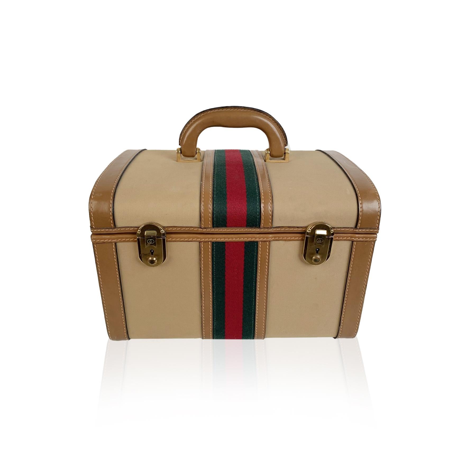 Splendid vintage train case by GUCCI, from the early 1970s. Crafted in beige canvas with tan genuine leather trim and handle. It features green/red/green striped detailing and gold-tone metal hardware. Double front key closure (key is included).