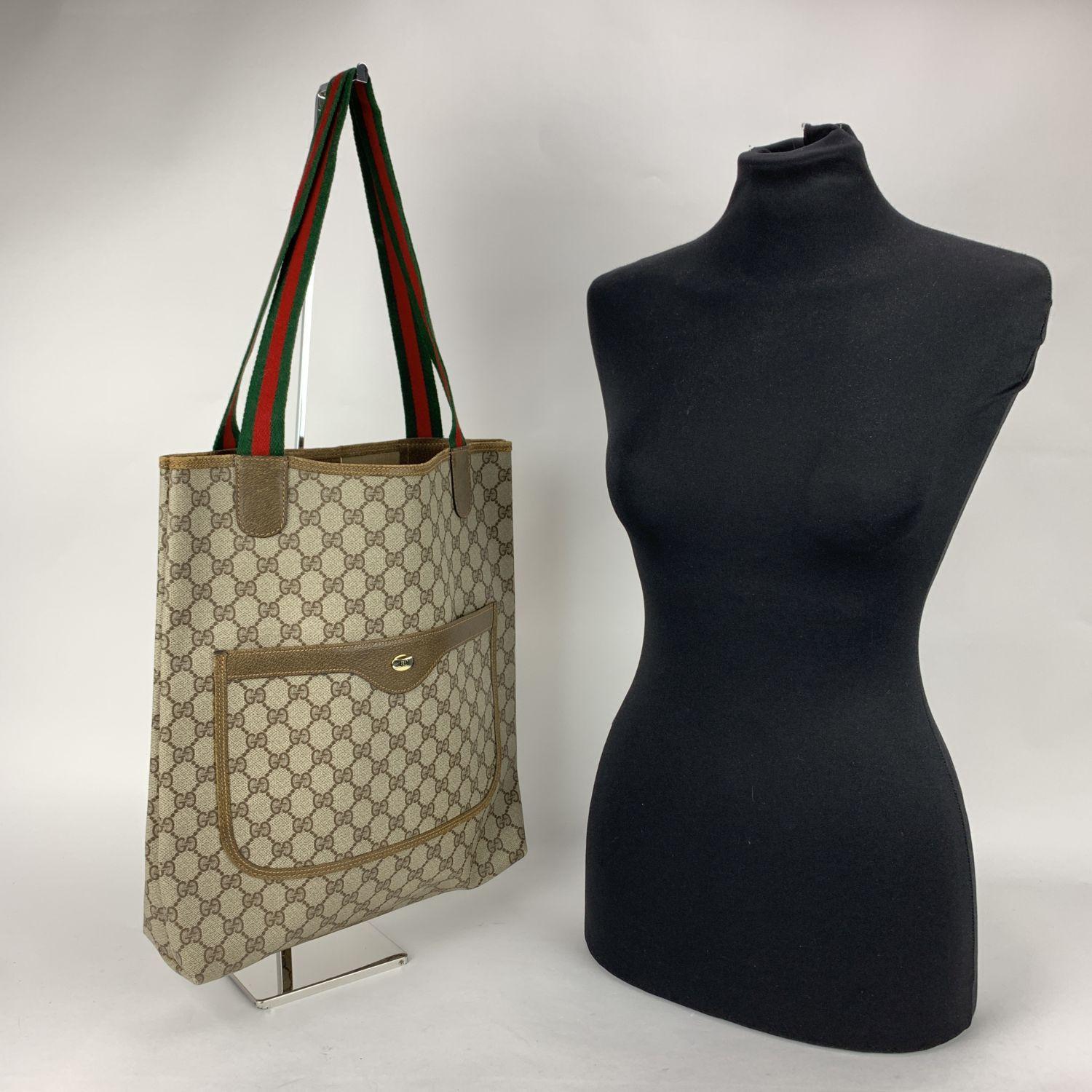 Beautiful Gucci tote made in monogram canvas with tan leather trim. Green/Red/Green striped canvas shoulder straps. 1 front patch pocket. Enameled GG- GUCCI logo tab on the front. Beige canvas lining. 'GUCCI Accessory collection - Made in Italy' tag