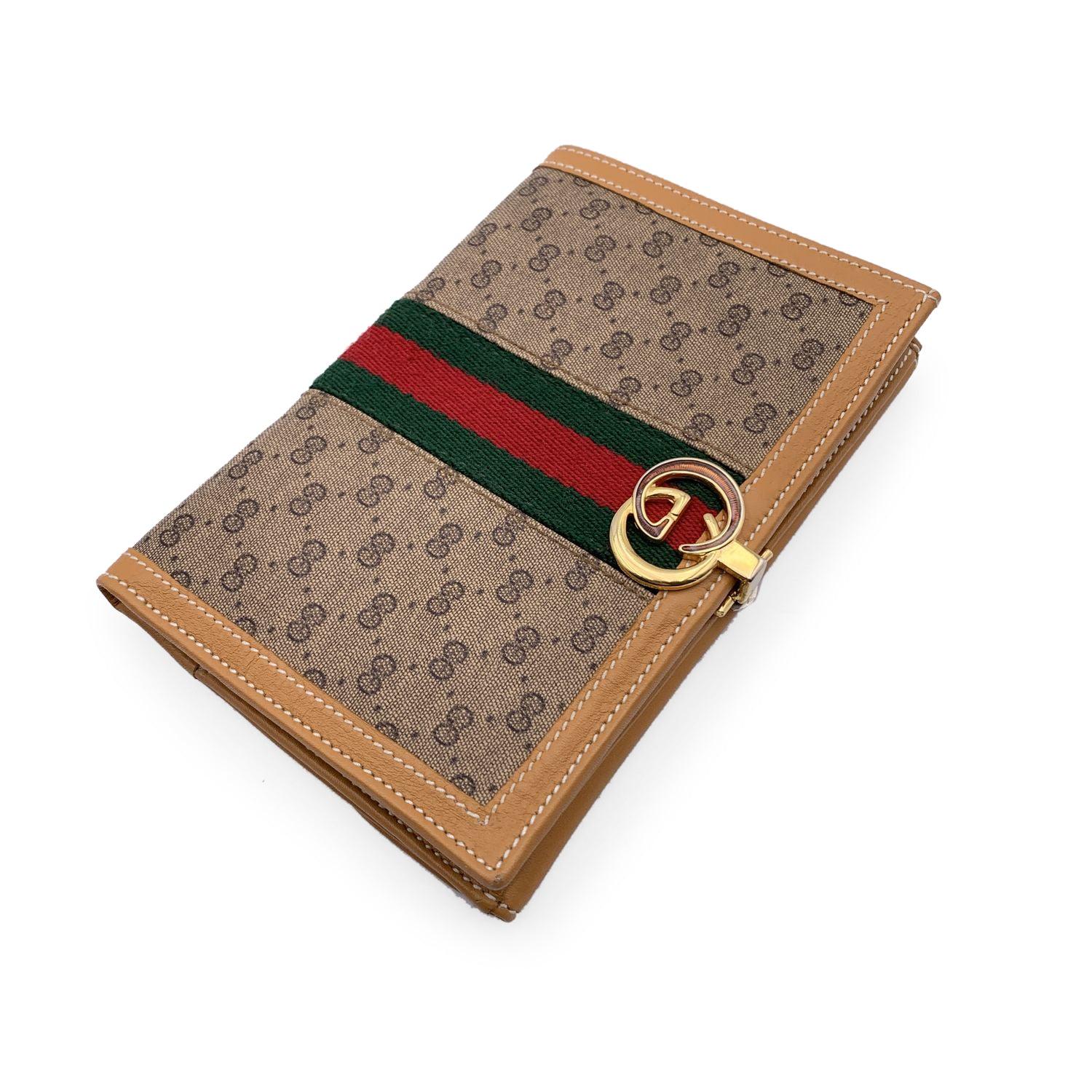 Vintage Gucci compact wallet, crafted in beige monogram canvas and leather with green/red/green stripes detailing. Gold metal enameled GG - GUCCI clasp closure. Back coin compartment with flap and snap button closure. It opens to a bill compartments