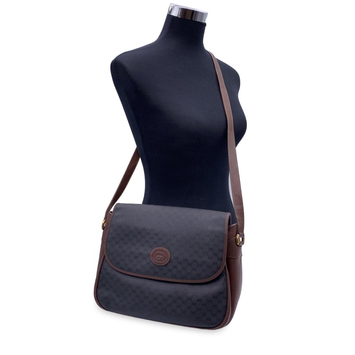 Gucci black monogram canvas shoulder bag with brown leather shoulder strap and trim. The bag features a front flap with magnetic button closure. 1 pocket under the flap. Canvas lining with 1 side zip pocket inside. 'Gucci - Italy' crest tag inside