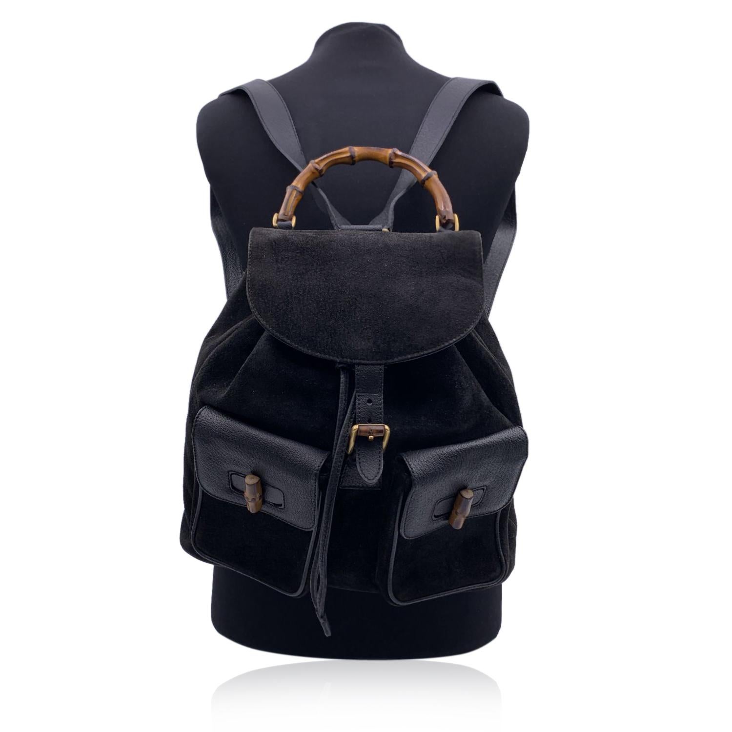 Vintage backpack by Gucci, crafted in black suede and leather. It features Bamboo handle and and knobs. Flap with buckle closure and drawstring top opening. Internal black diamond lining. 1 side zipper pocket inside (the zipper pull is missing).