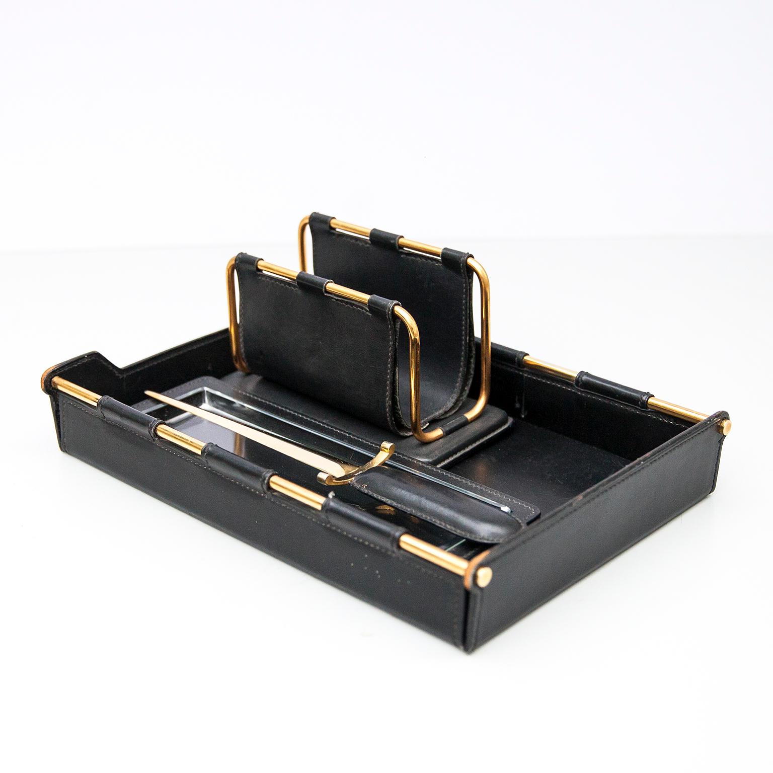 Stunning Gucci desk set made of black leather and brass. Four pieces include: massive desktop blotter or pad, huge letter opener, envelope holder and a leather pen holder with glass inlay. All pieces marked Gucci. Beautiful set. Very good vintage