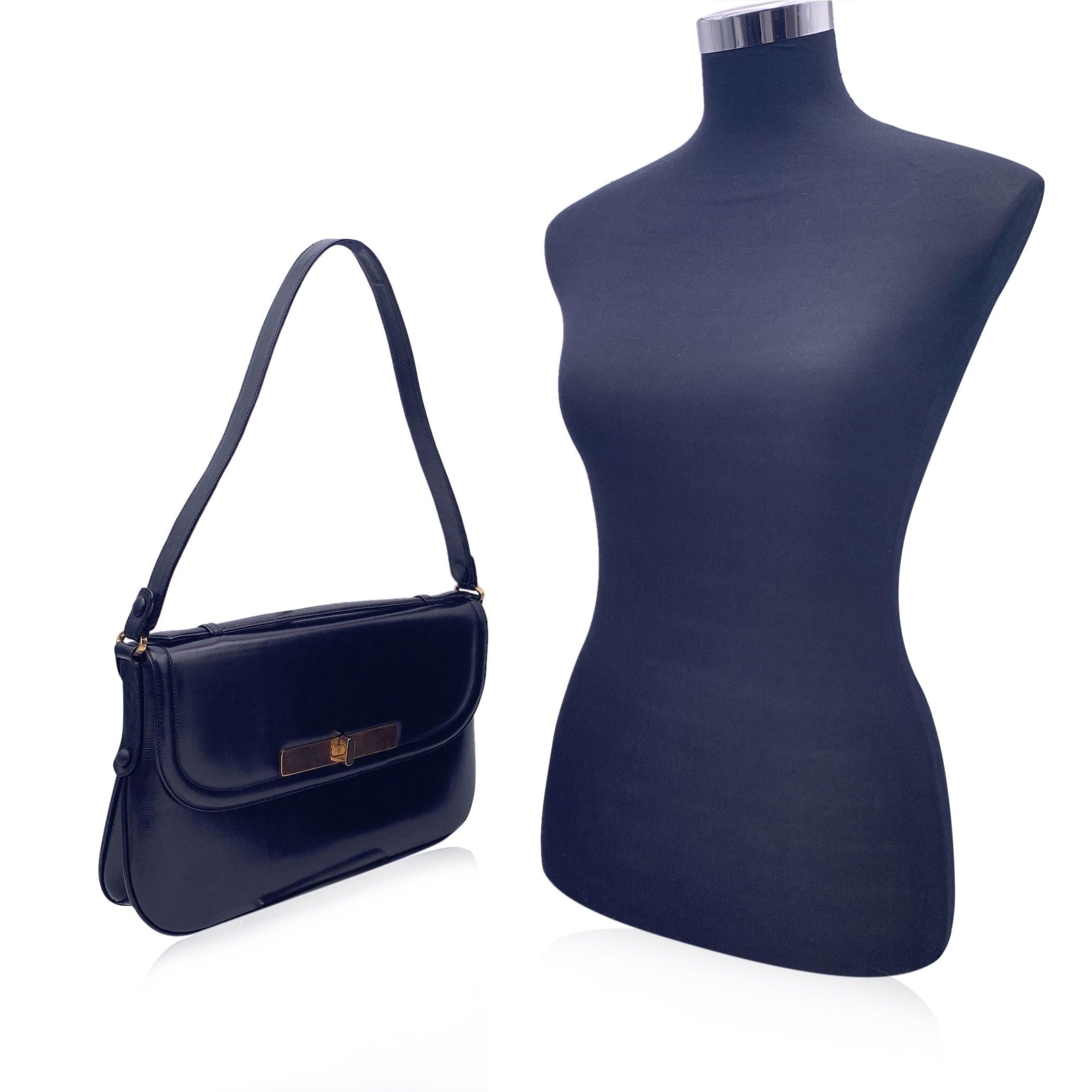 Vintage Gucci shoulder bag in black leather. Top handle and shoulder strap. Flap closure with gold metal closure on the front. Black leather lining. 2 side zip pockets inside. Matching coin purse included. 'Made in Italy by GUCCI' tag inside