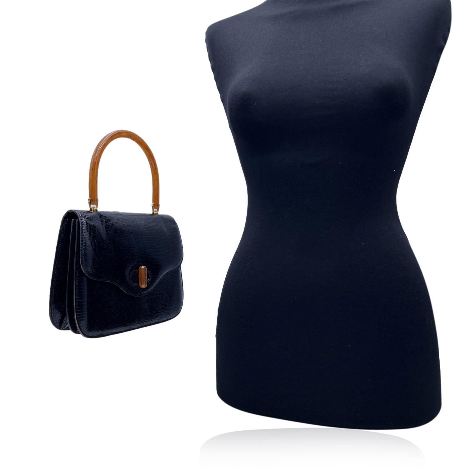 Vintage Gucci black lizard leather handbag. It features orange lucite handle and front twist closure. Black leather lining. 2 sections inside. 2 side open pockets and 1 side zip pocket inside with gold metal Gucci crest zipper pull. 'Made in Italy