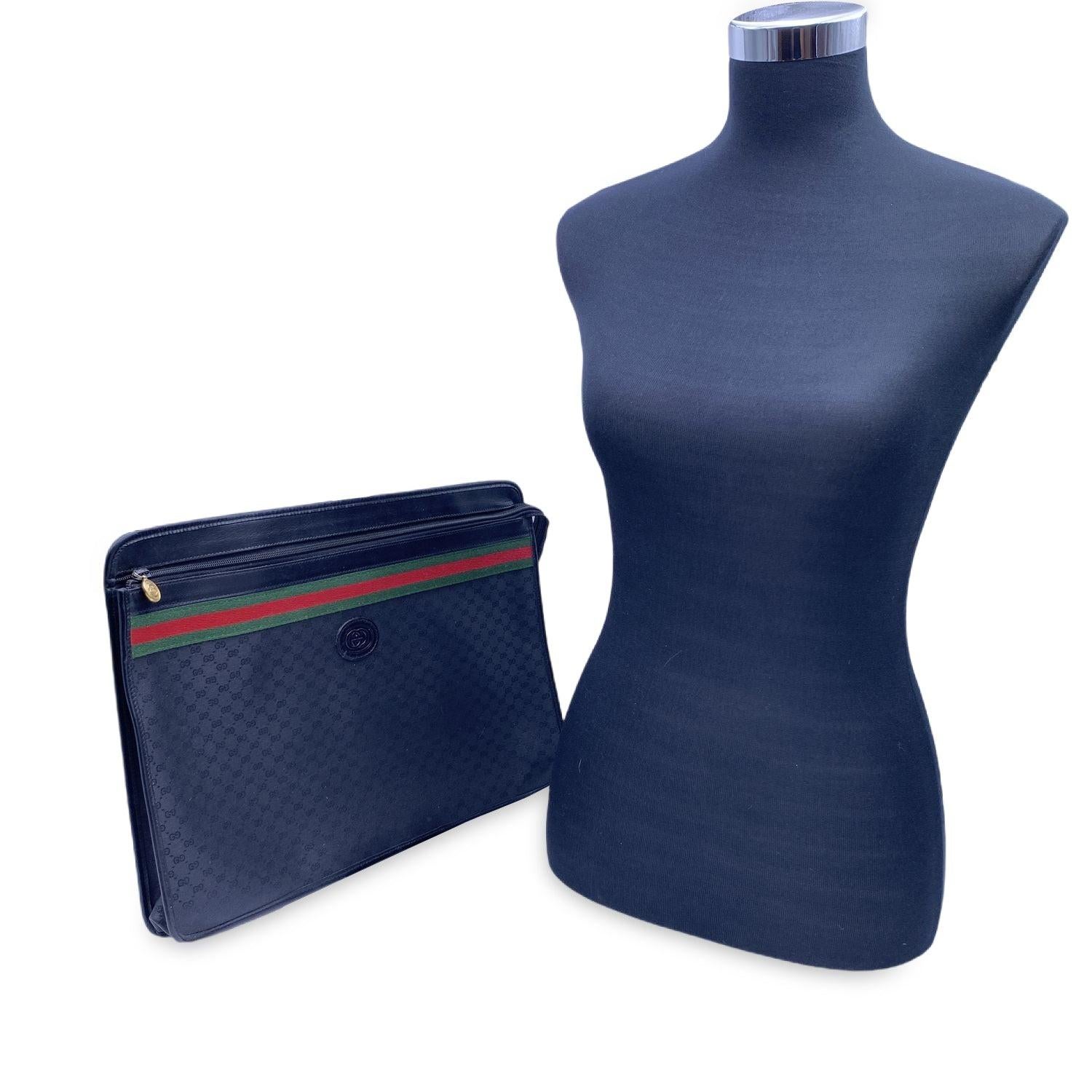 Bolso o cartera vintage Gucci negro 'GG' monograma de lona con cremallera. Presenta un cierre de cremallera frontal y un parche con el logotipo de GG en la parte delantera, así como las clásicas rayas rojas y verdes de GUCCI. El interior de la