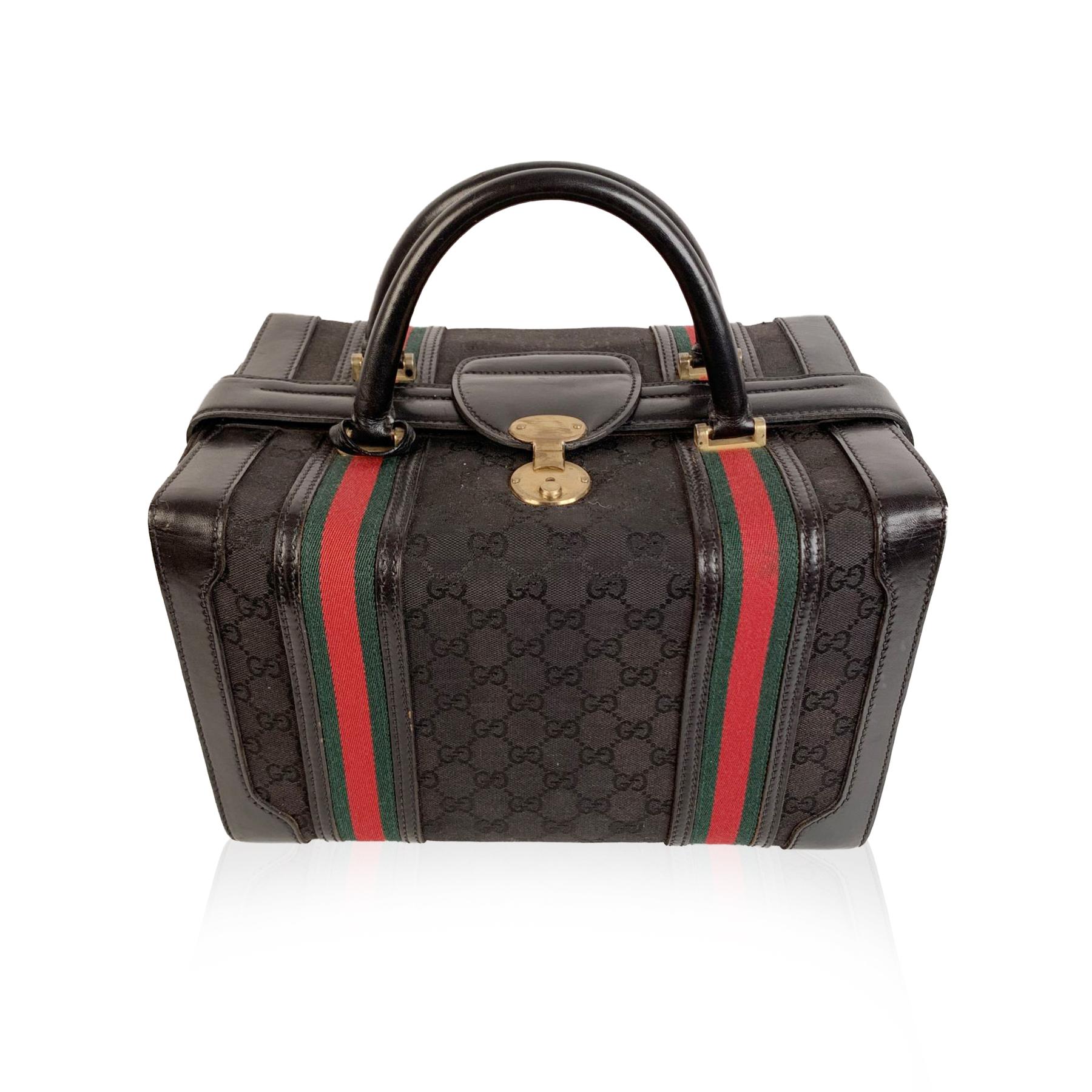 Splendid vintage train case by GUCCI, from the early 1970s. Crafted in black monogram canvas with black genuine leather trim and handles. It features double green/red/green striped detailing and gold-tone metal hardware. It closes with upper lock