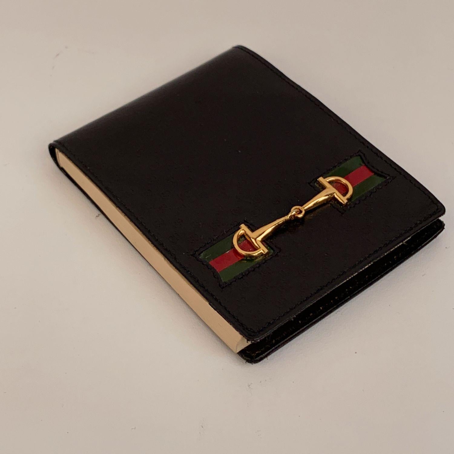 Vintage Gucci pocket notepad with pen. Crafted in black leather with small embossed monograms. It features green/red/green striped and gold metal horsebit on the front. The original Gucci block with blank pages is present. Small gold metal pen