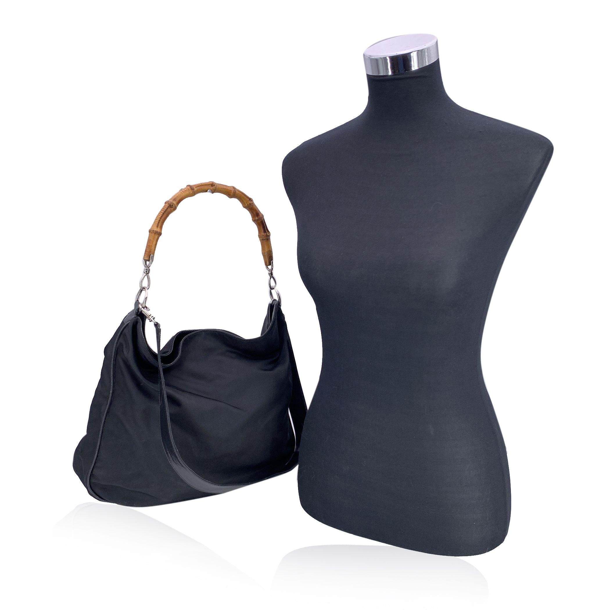 Ce magnifique sac hobo de Gucci est réalisé en toile de nylon noire et présente la poignée en bambou signature de la marque, pour une esthétique à la fois raffinée et moderne. Le sac se ferme à l'aide d'un bouton magnétique supérieur pour un accès