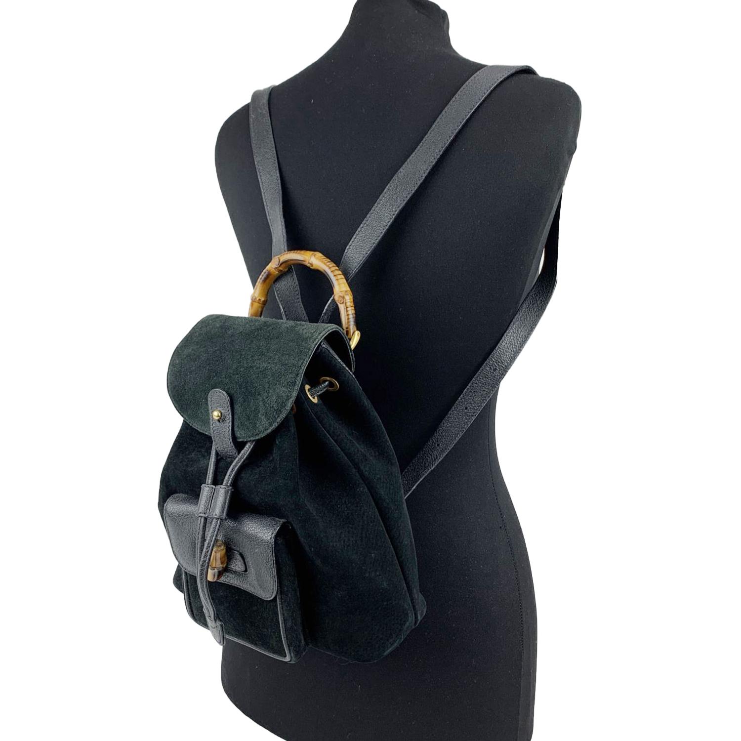 Vintage small backpack by Gucci, crafted in black suede and leather. It features Bamboo handle and and knob. 1 front pocket with twist lock closure. Flap closure and drawstring top opening. gold metal hardware. Internal diamond lining. 1 side zip