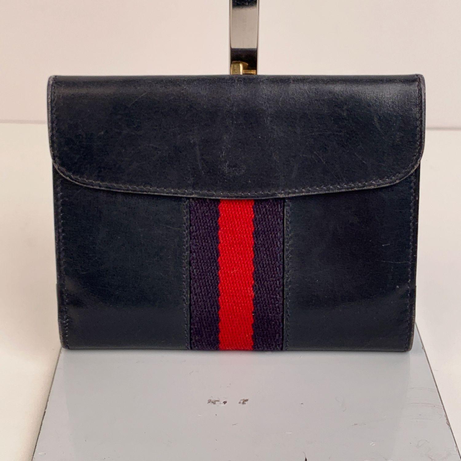 Vintage Gucci compact wallet, crafted in blue leather with blue/red/blue stripes detailing. Gold metal enameled GG - GUCCI clasp closure. Back coin compartment with flap and snap button closure. It opens to a bill compartments and 4 open pockets.