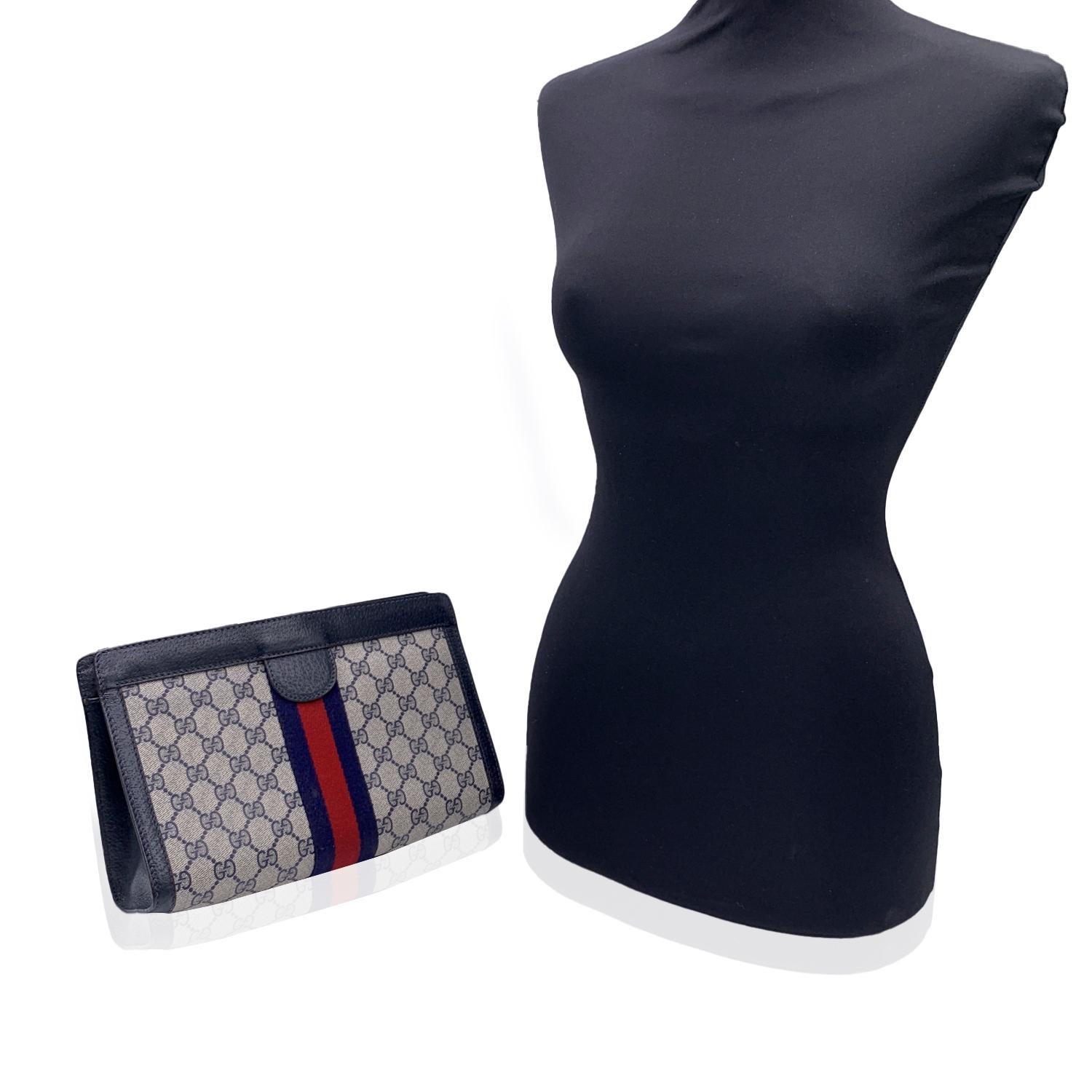 Gucci Vintage Blue Monogram Canvas Cosmetic Bag Clutch with Stripes. Blue Monogram Canvas with Genuine Leather trim. Blue/Red/blue stripes around the bag. Upper hook and loop closure. Blue lining. 