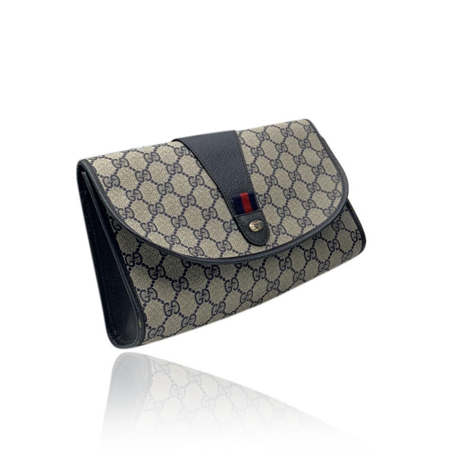 Gucci Vintage Blue Monogram Canvas Clutch Bag. Blue Monogram Canvas with Genuine Leather trim. Blue/Red/Blue striped canvas detail on the front with oval GG - GUCCI logo tab on the front. Flap with magnetic button closure. Blue leather lining. 1