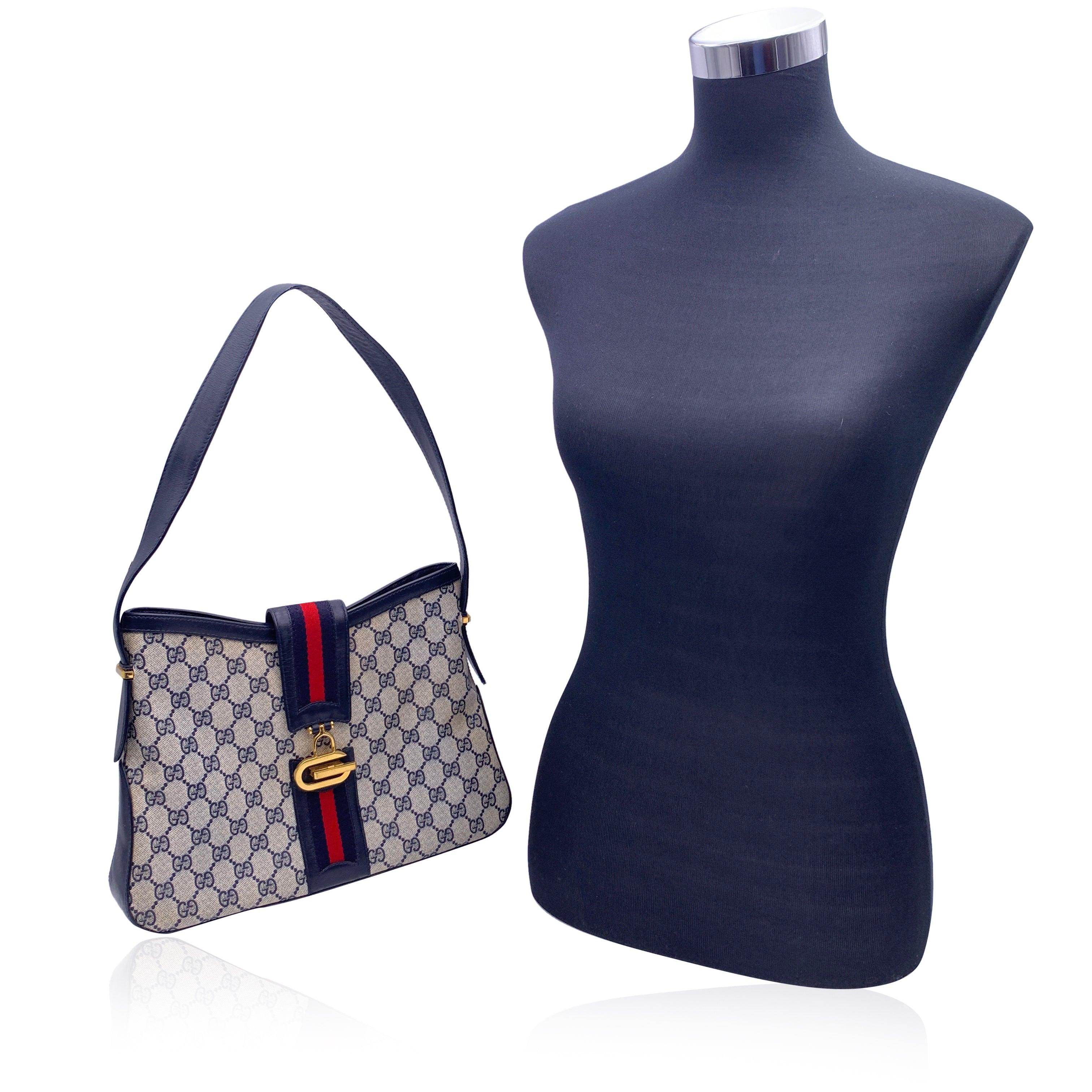 Gucci vintage shoulder bag. Monogram canvas with blue genuine leather trim and shoulder strap. Fold over strap with clasp closure. Blue/red/blue striped detailing. 1 side zip pocket and 1 side open pocket inside.'Made in Italy by Gucci' embossed