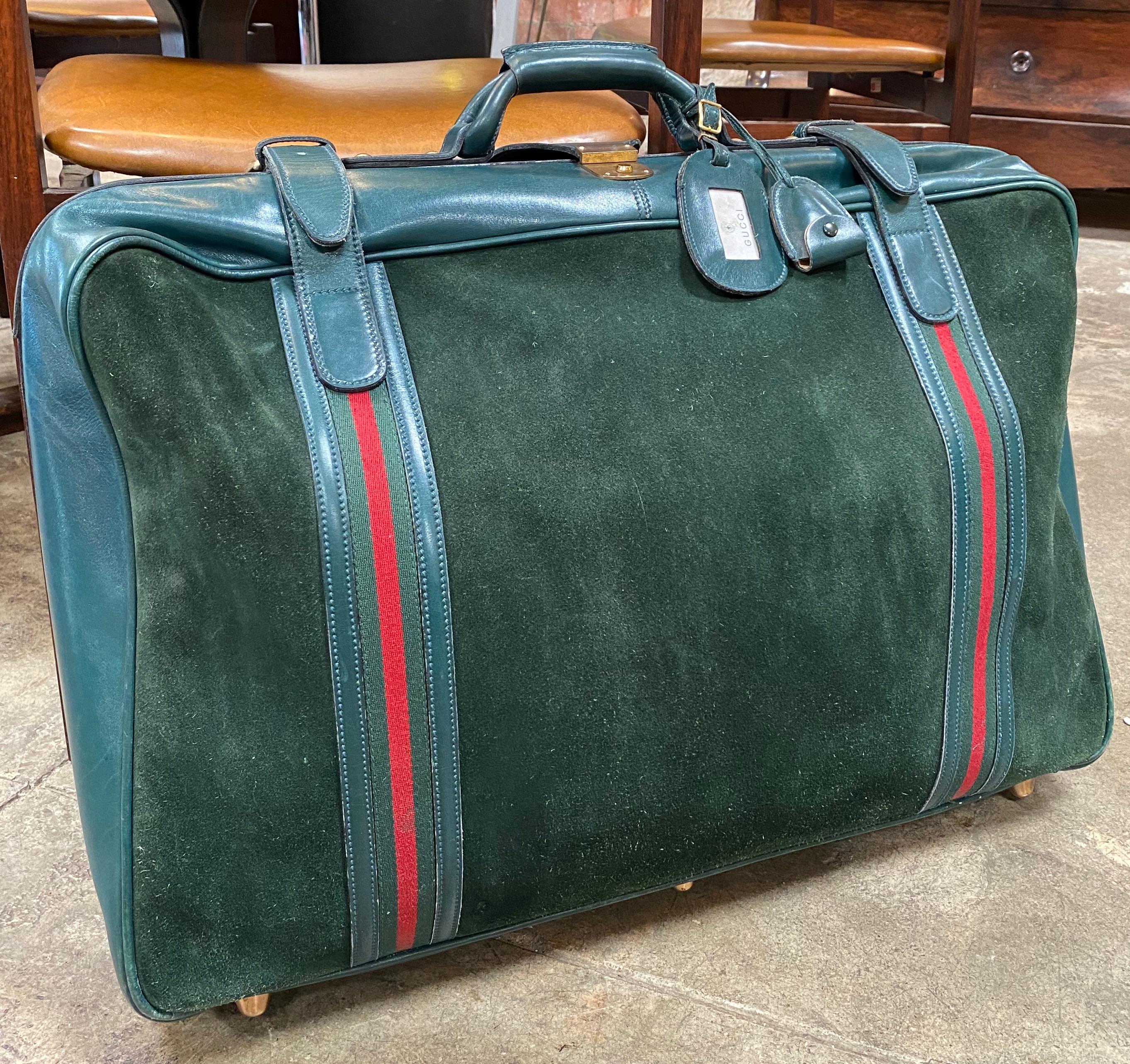 Vintage Gucci medium/large suitcase crafted in blue suede with blue leather trim. Gold metal hardware. Double wraparound zipper and fold over strap with security key closure (key is included). Additional double buckled straps on the sides of the