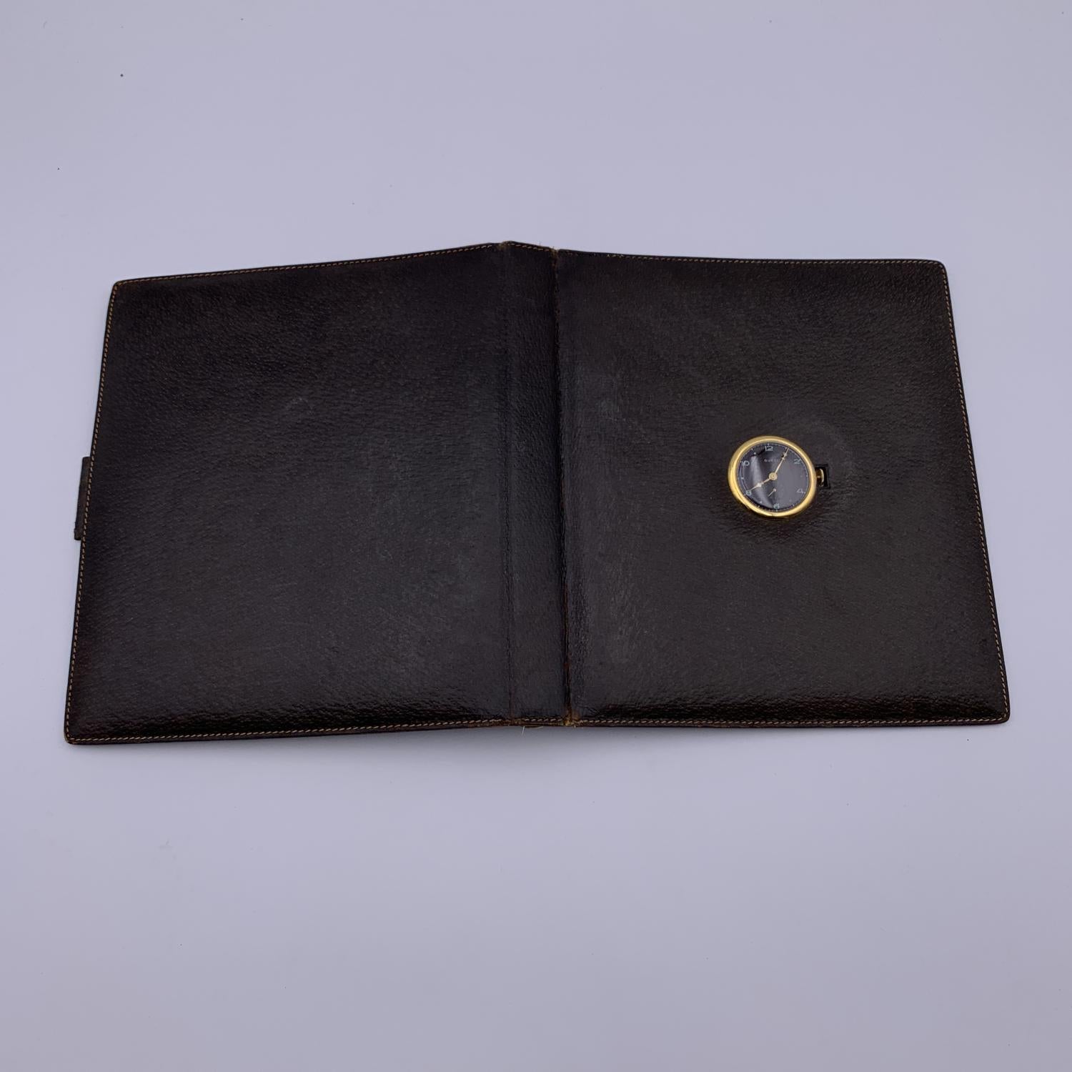 Beautiful and rare vintage agenda cover by GUCCI crafted in brown leather. It features a built-in watch with manual winding in the cover. 5 ring binder. Gold metal hardware. Green leather inside with 1 side slot for paper and 1 pen holder. 'Made in