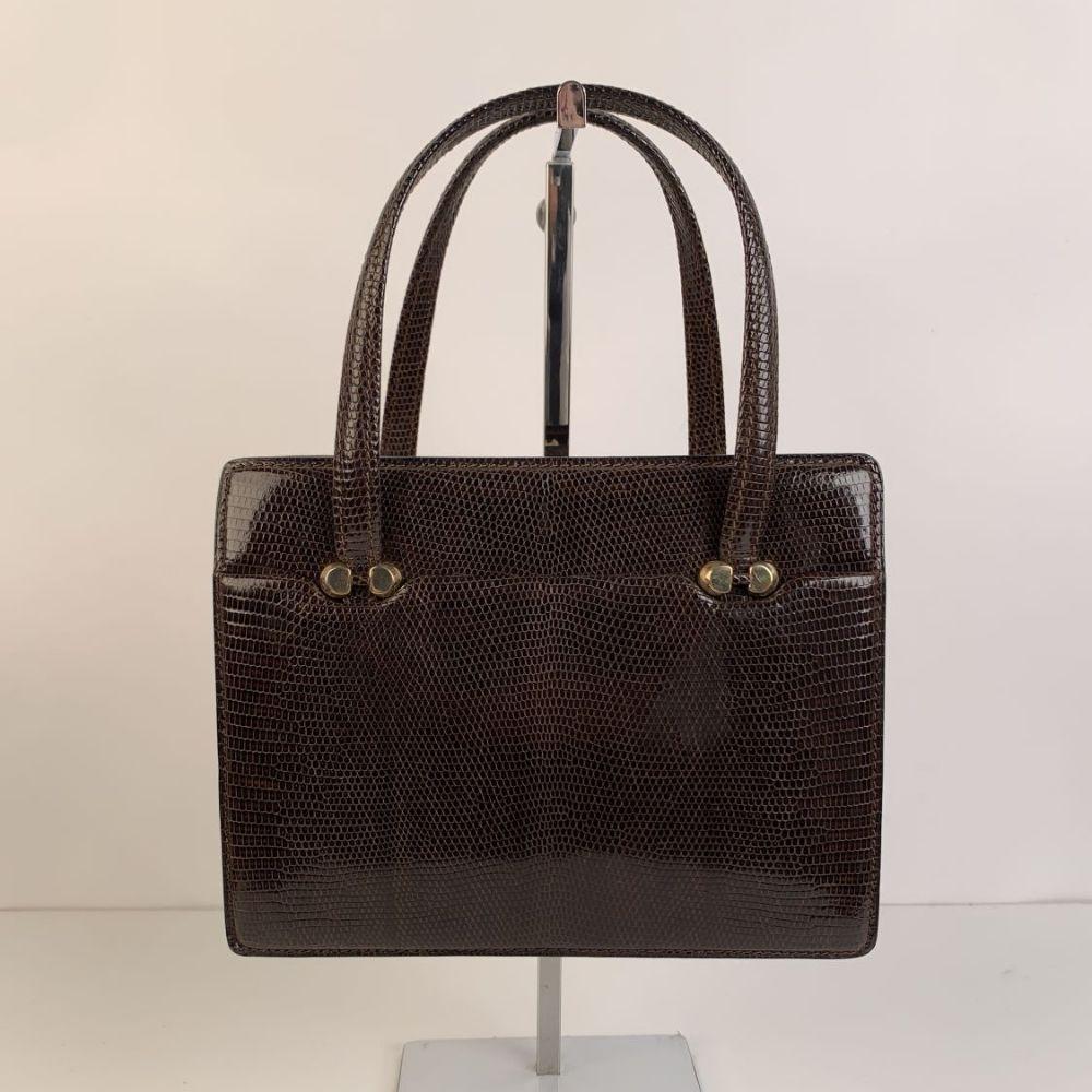 - Gucci Vintage Top Handle Bag
- Brown Lizard Leather
- Gold metal hardware
- 1 flat open compartment on the front and 1 on the back
- Clasp closure on top
- Brown leather lining
- 2 side open pockets and 1 side zip pocket inside
- Removable