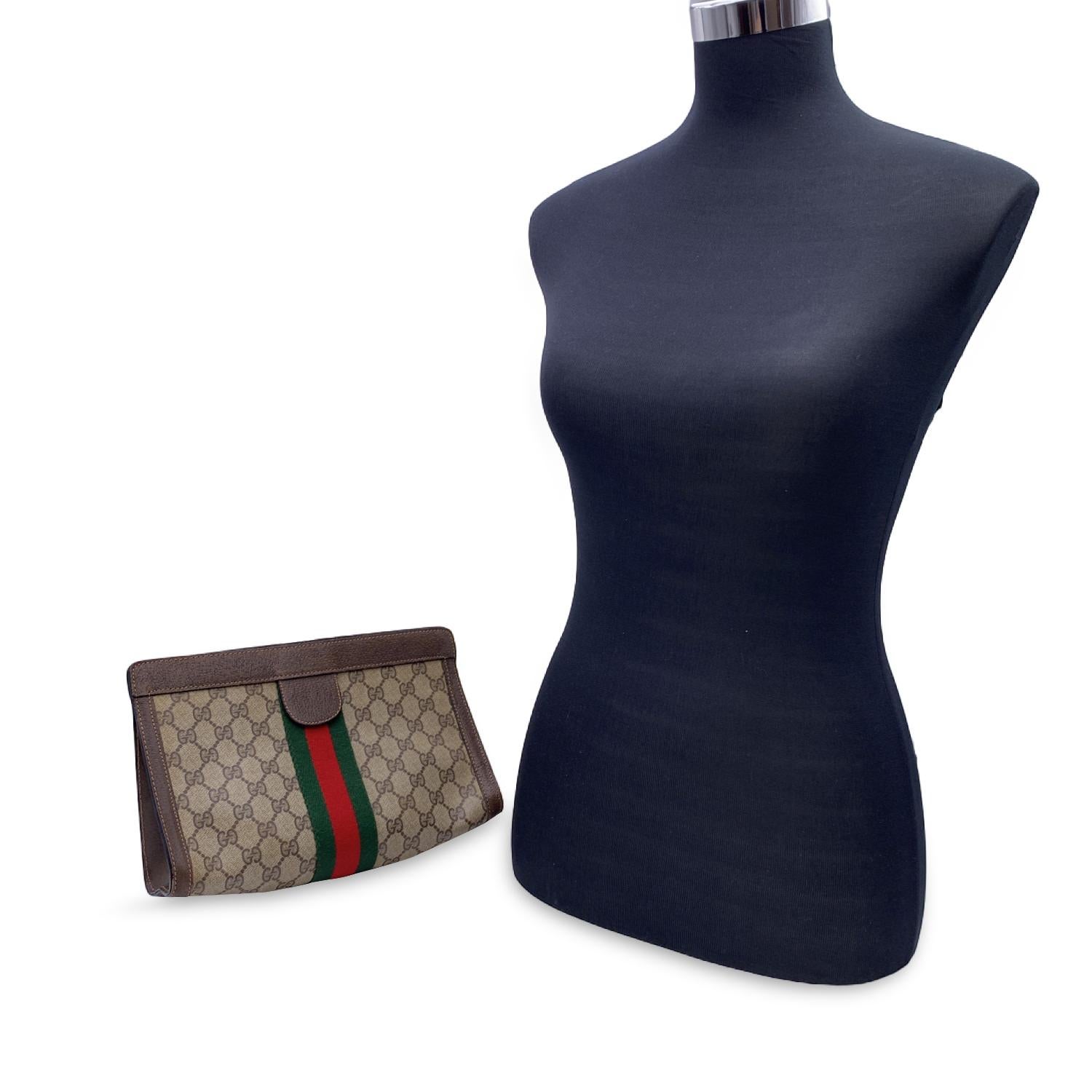 Gucci Vintage Brown Monogram Canvas Cosmetic Bag Clutch with Stripe. Brown Monogram Canvas with Genuine Leather trim. Green/Red/Green stripes around the bag. Upper hook and loop closure. Waterproof lining. 