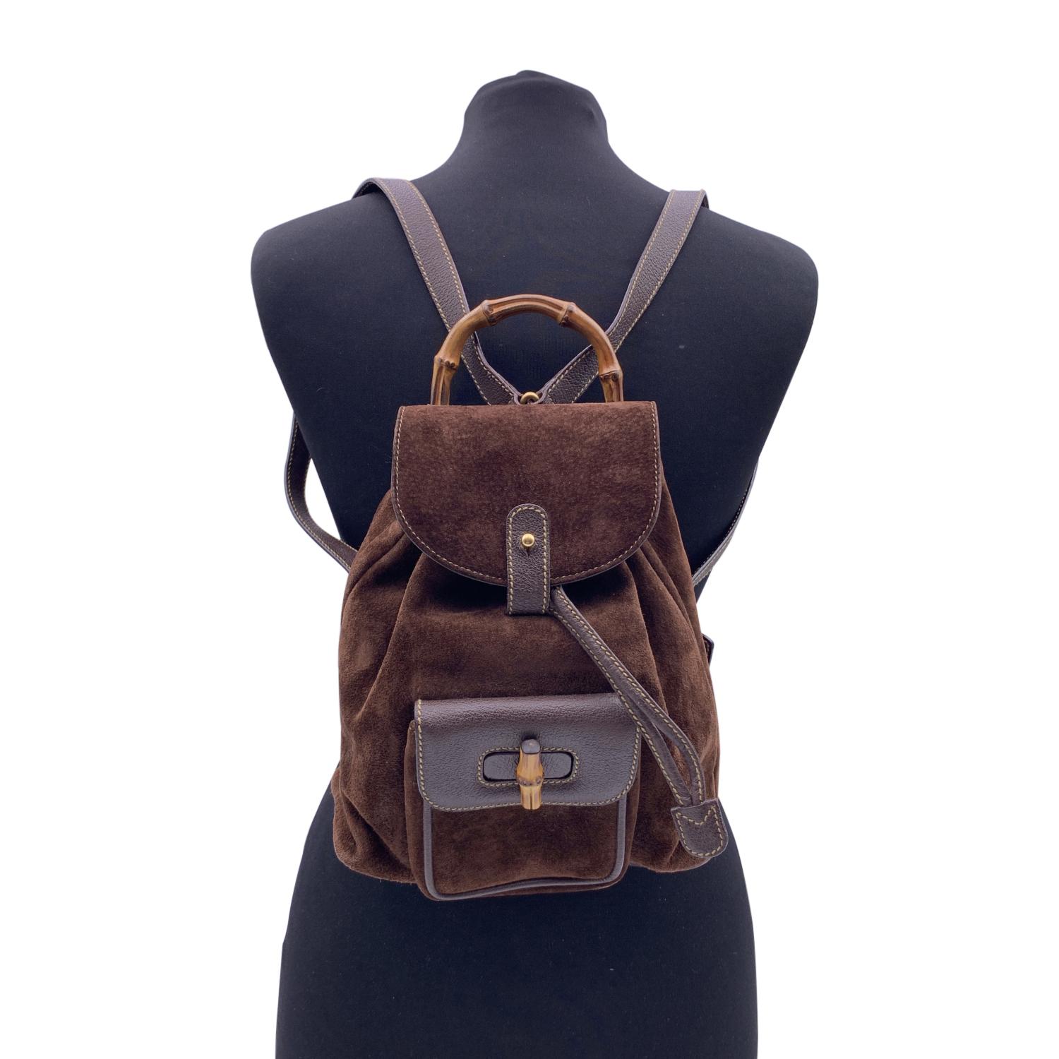 Vintage small backpack by Gucci, crafted in brown canvas and leather. It features Bamboo handle and and knob. 1 front pocket with twist lock closure. Flap closure and drawstring top opening. gold metal hardware. Internal diamond lining. 1 side zip