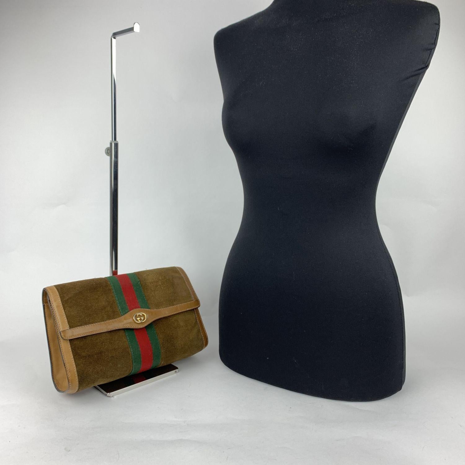 Gucci Vintage flap cosmetic bag with stripes. Brown suede with Genuine Leather trim. Green/Red/Green stripes around the bag. Gold metal GG - GUCCI logo on the front. Flap with button closure on the front. Waterproof lining with monogram pattern.