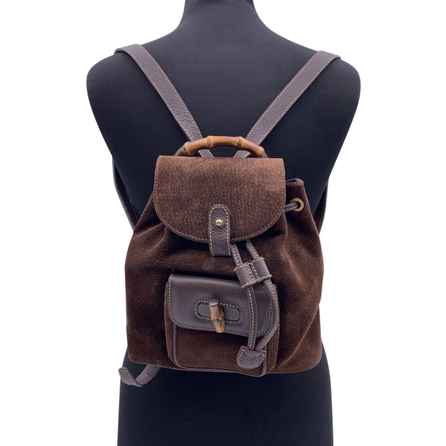 Vintage small backpack by Gucci, crafted in brown suede and leather. It features Bamboo handle and and knob. 1 front pocket with twist lock closure. Flap closure and drawstring top opening. gold metal hardware. Internal diamond lining. 1 side zip