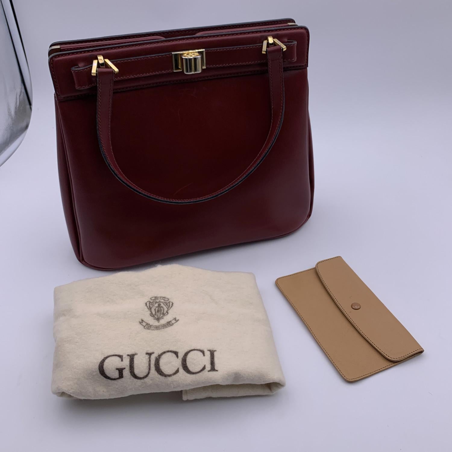Beautiful Gucci handbag made in burgundy leather with gold metal hardware. Front turn lock closure. Tan leather lining. 2 main sections inside 3 side open pocket, 1 lipstick holder, 1 side zip pocket and 1 leather removable pouch. 'Made in Italy by