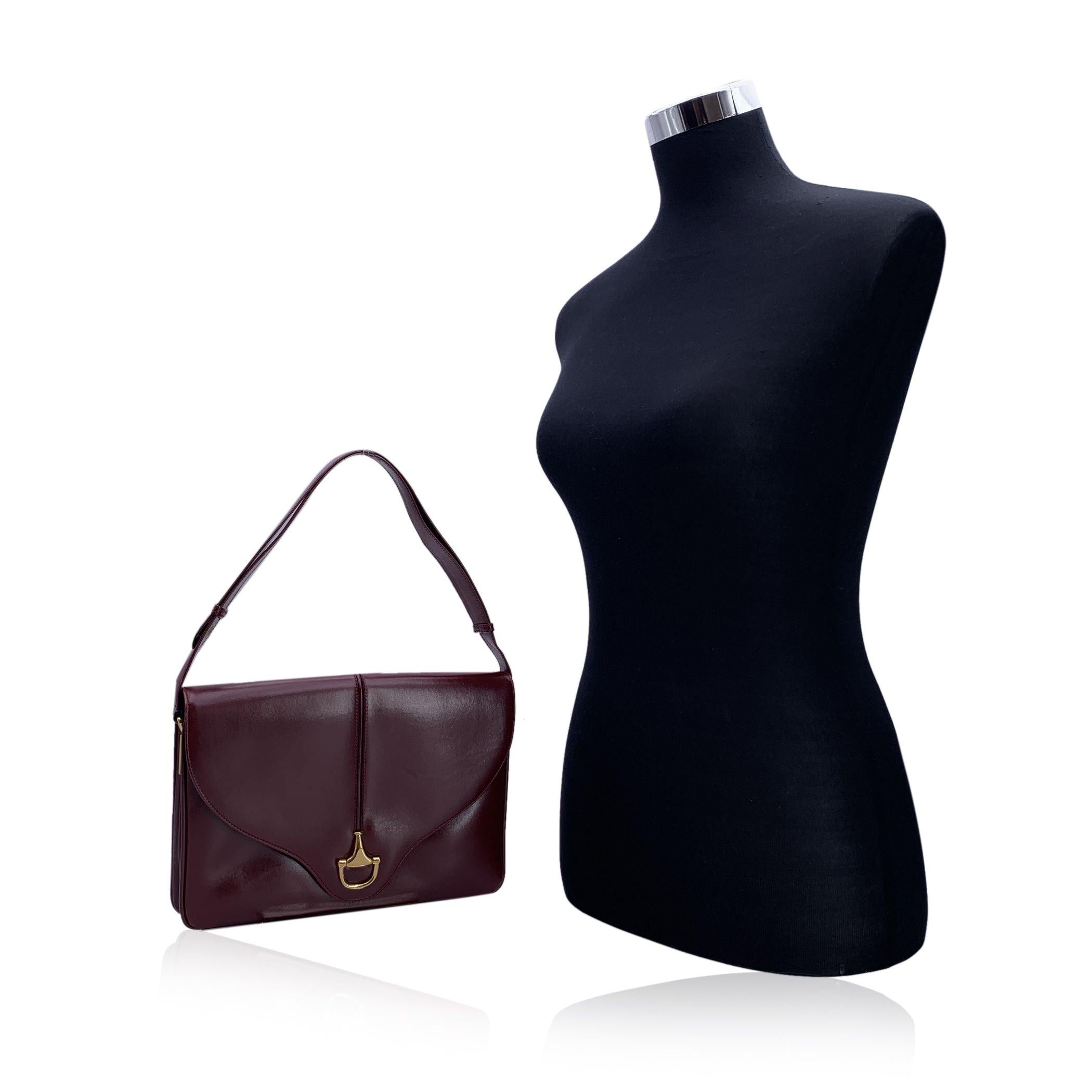 Vintage Gucci shoulder bag in burgduny leather. The bag featuresa gold metal half- horsebit on the front. Flap withbutton closure. Leather lining . 2 main sections and 1 middle zip section inside. Adjustable shoulder strap. 'Gucci Italy' crest