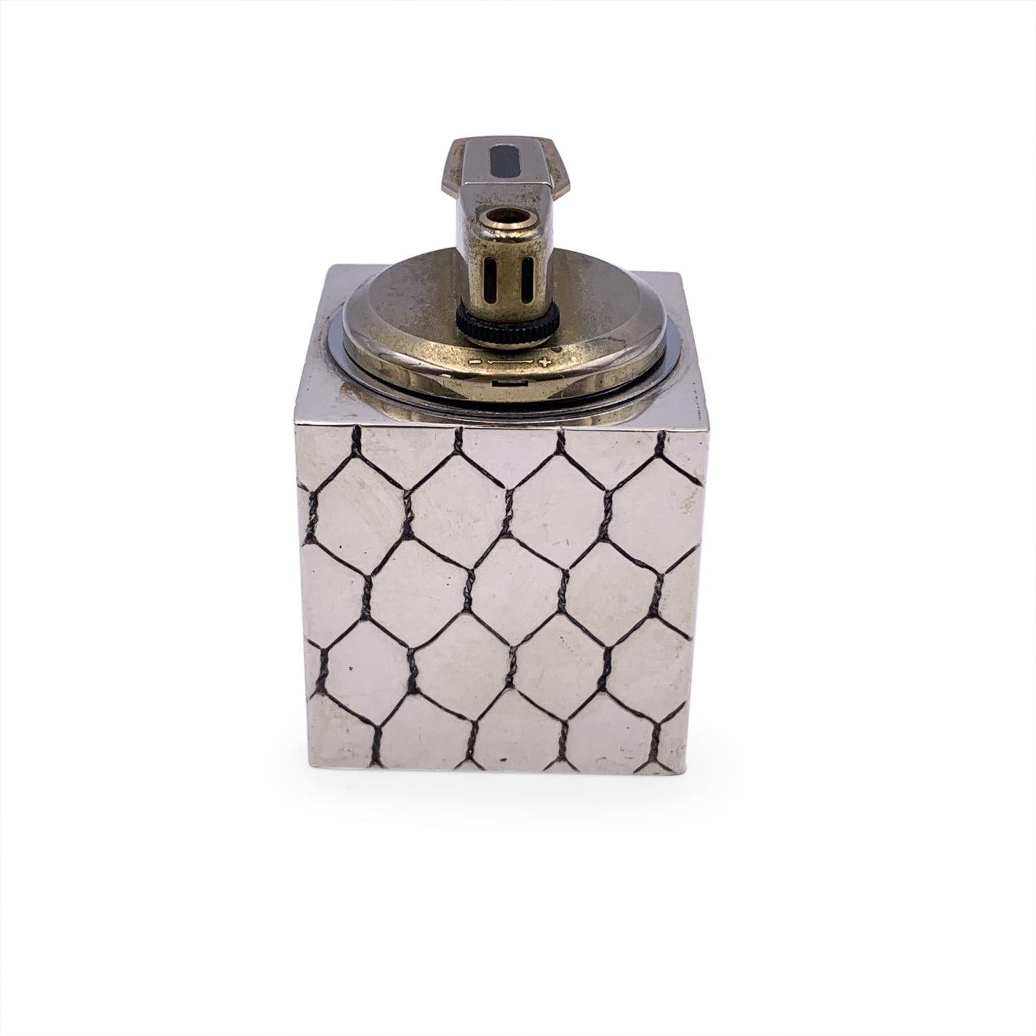 Vintage GUCCI table lighter. Cube-shaped. Silver metal with engraved motif. GG logo on the front. Marked 'Gucci - Italy' on the base. Height: 3 inches - 7.6 cm. Width: 2 inches - 5.1 cm. Details MATERIAL: Metal COLOR: Silver MODEL: n.a. GENDER: