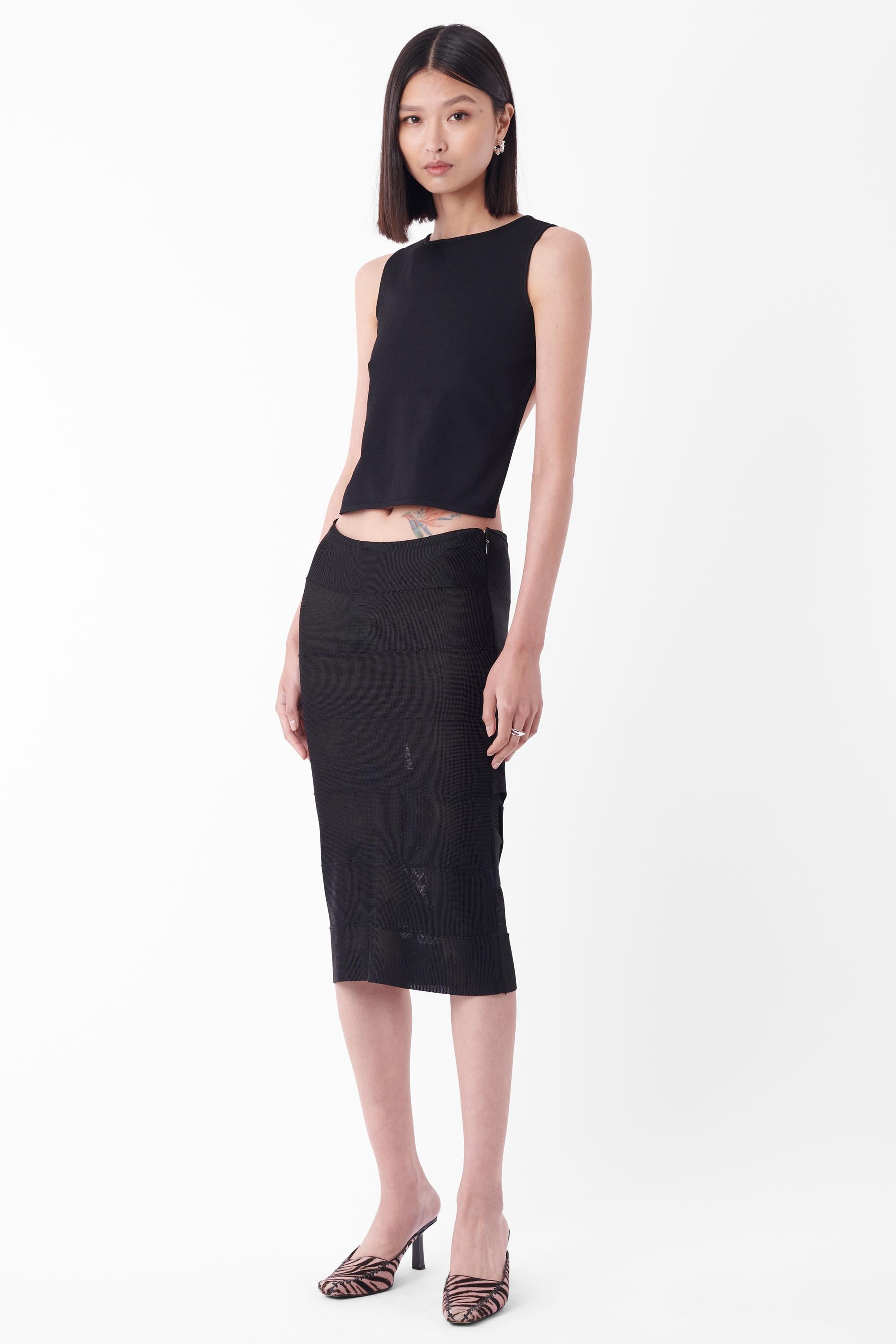 Vintage Tom Ford for Gucci Otoño Invierno 2002 Falda negra bodycon midi. Lleva dos tirantes negros cruzados en la parte inferior trasera y delantera . Se abrocha con una cremallera lateral invisible negra.

Marca: Gucci
Talla: RU 6
Color: