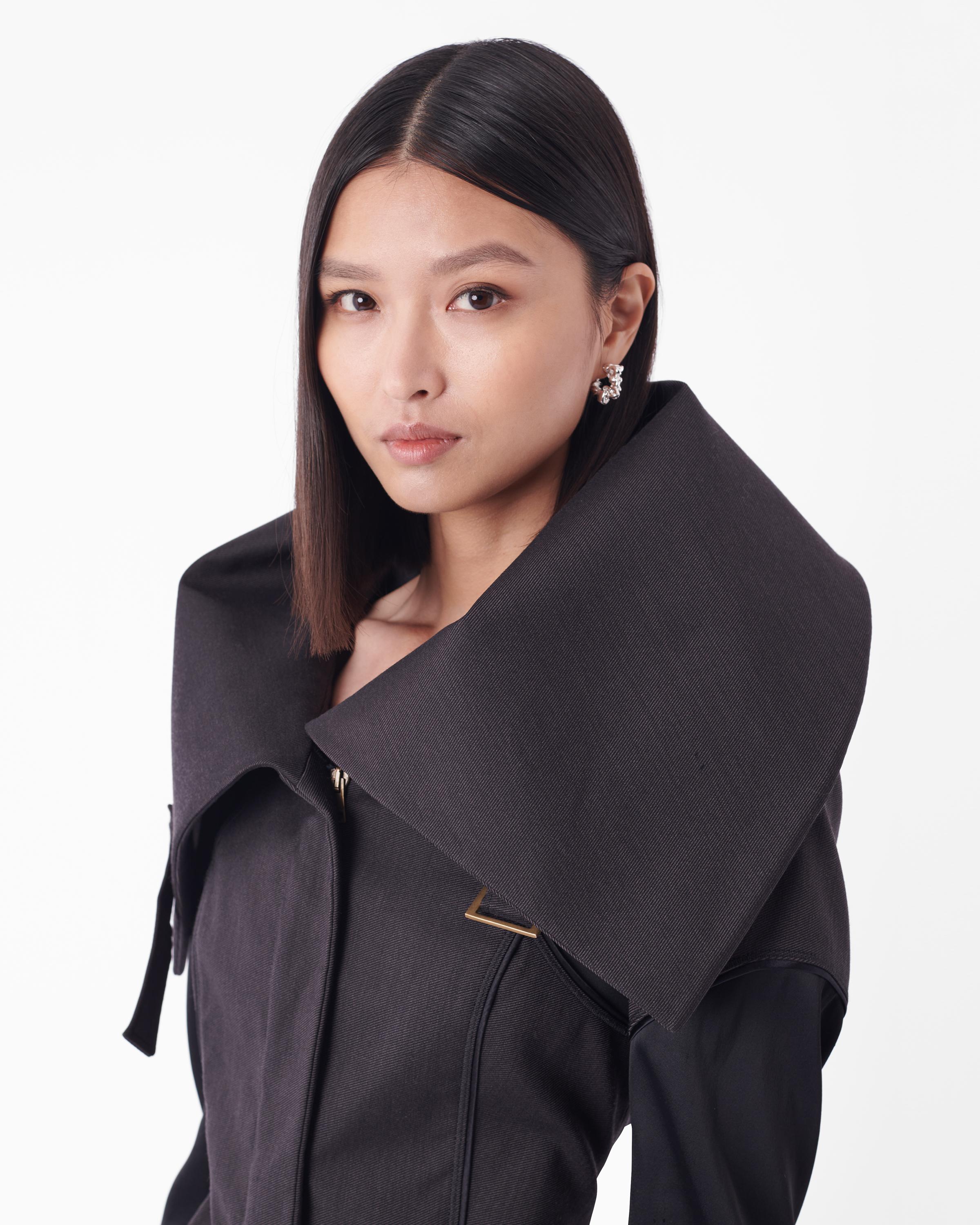 Veste à col Tom Ford for Gucci Fall Winter 2003, défilé 11. Il est doté d'une fermeture à glissière, de deux poches sur le devant, de coutures passepoilées, de poignets allongés en tissu contrasté et d'un col surdimensionné à porter de différentes