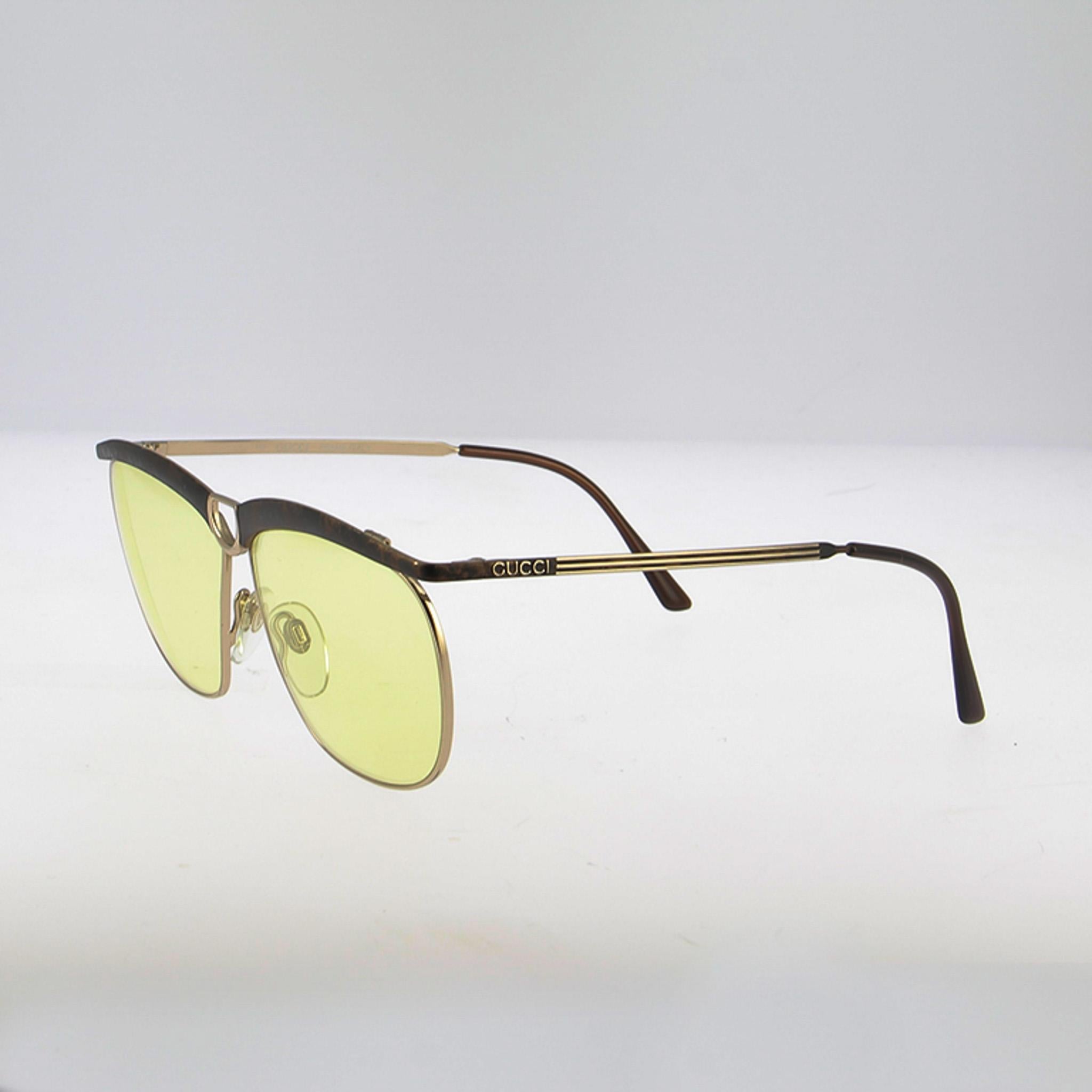 Con una montura Gucci de los años 70, estas gafas de sol capturan el espíritu retro-lujo de la maison. La línea suavizada de aviador cuadrado destaca con un borde de oro satinado rematado por una barra de carey en la ceja, un detalle cálido y