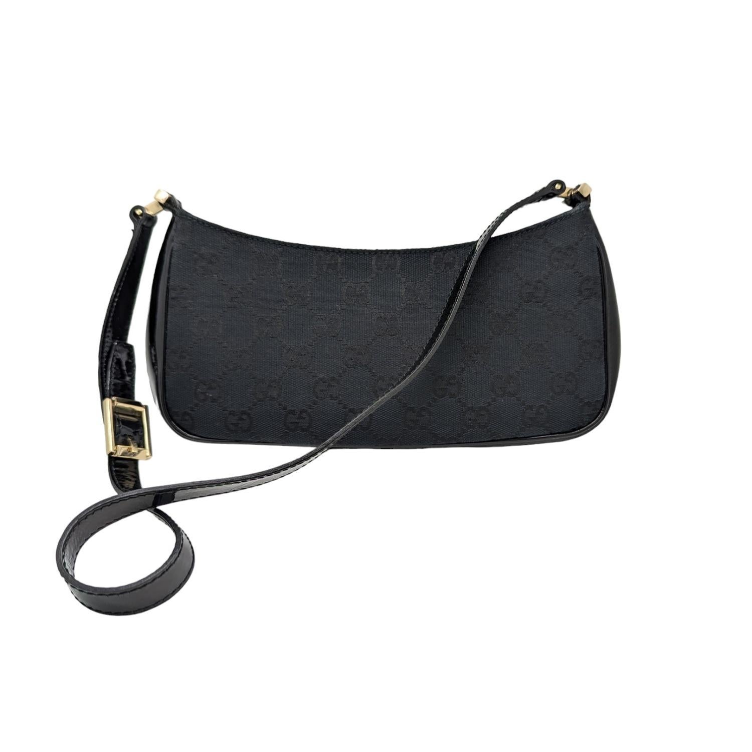 Indulge in luxury with this vintage Gucci GG canvas patent-trimmed baguette. The iconic black GG monogram adds a touch of elegance, while the gold-tone hardware and shoulder strap provide functionality. The spacious interior includes a zip pocket