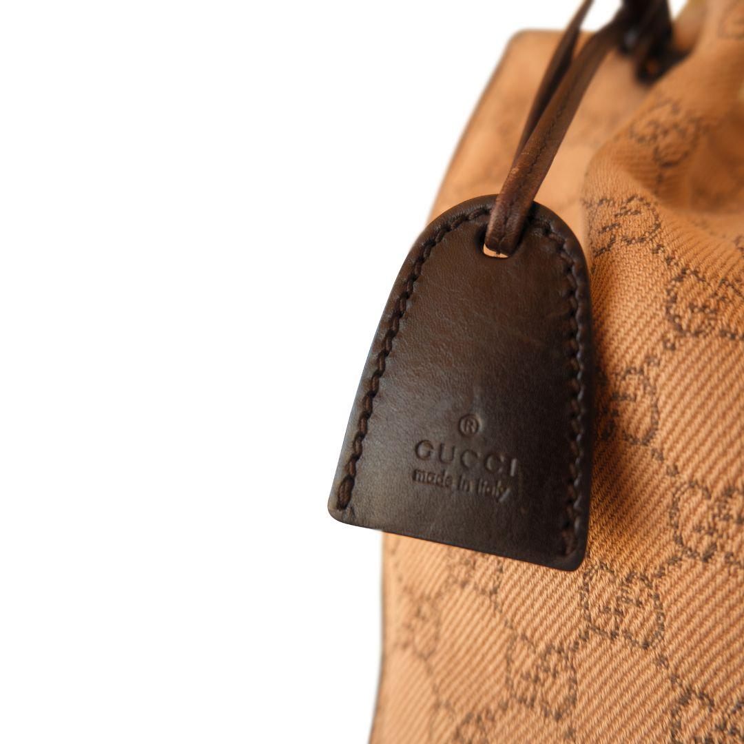 Gucci vintage GG monogram canvas tote in tan and brown.

Dark brown leather sides with matching internal pouch and leather logo hang tag. Sturdy leather straps attached with matching leather rings. Canvas lined interior.

Condition Details: Very