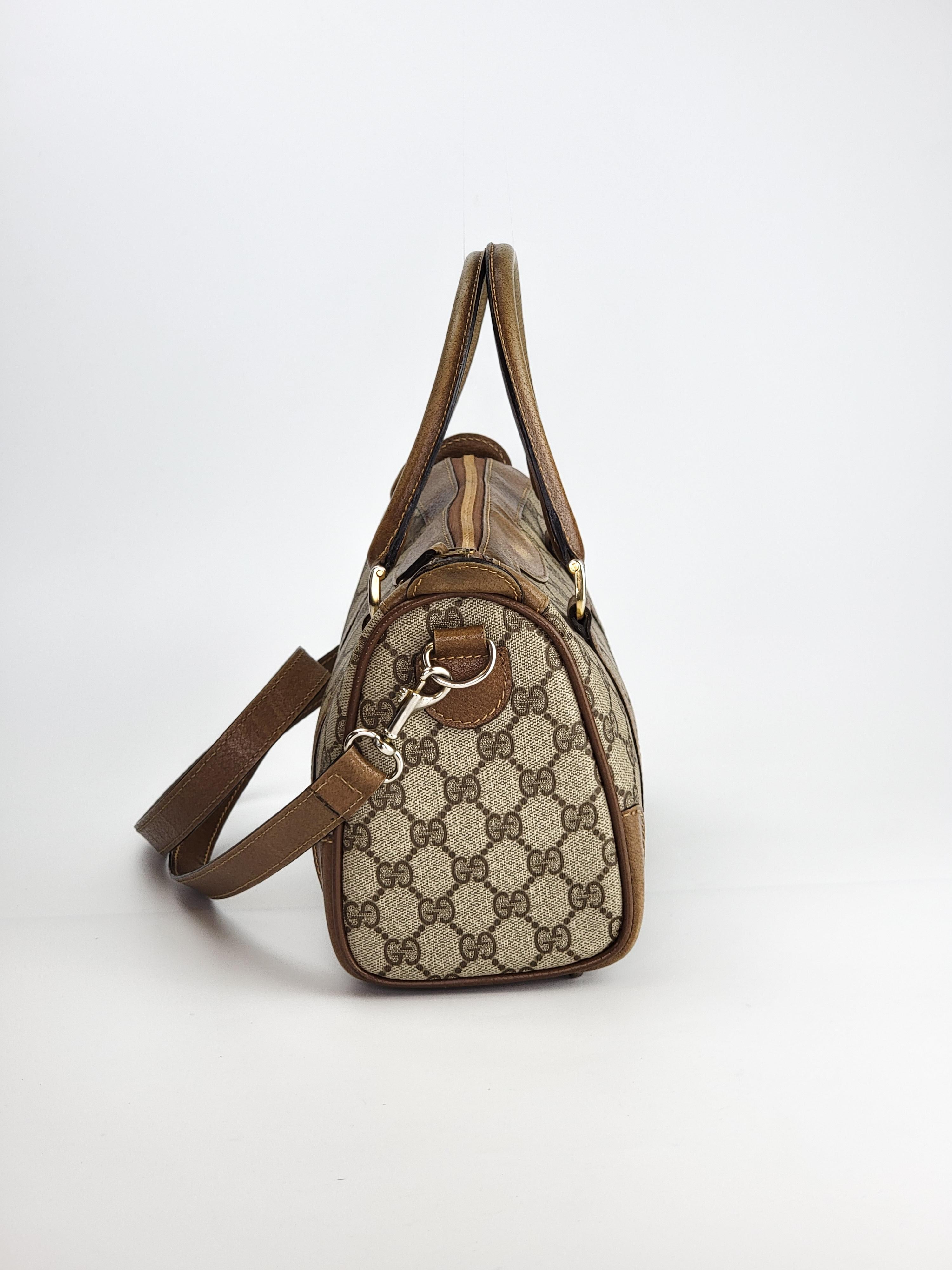 This vintage Gucci Boston bag is made with Gucci monogram supreme coated canvas with leather finishes. The bag measures 25 cm in length and features gold tone hardware, brown leather trim, dual rolled leather top handles, top zip closure. leather